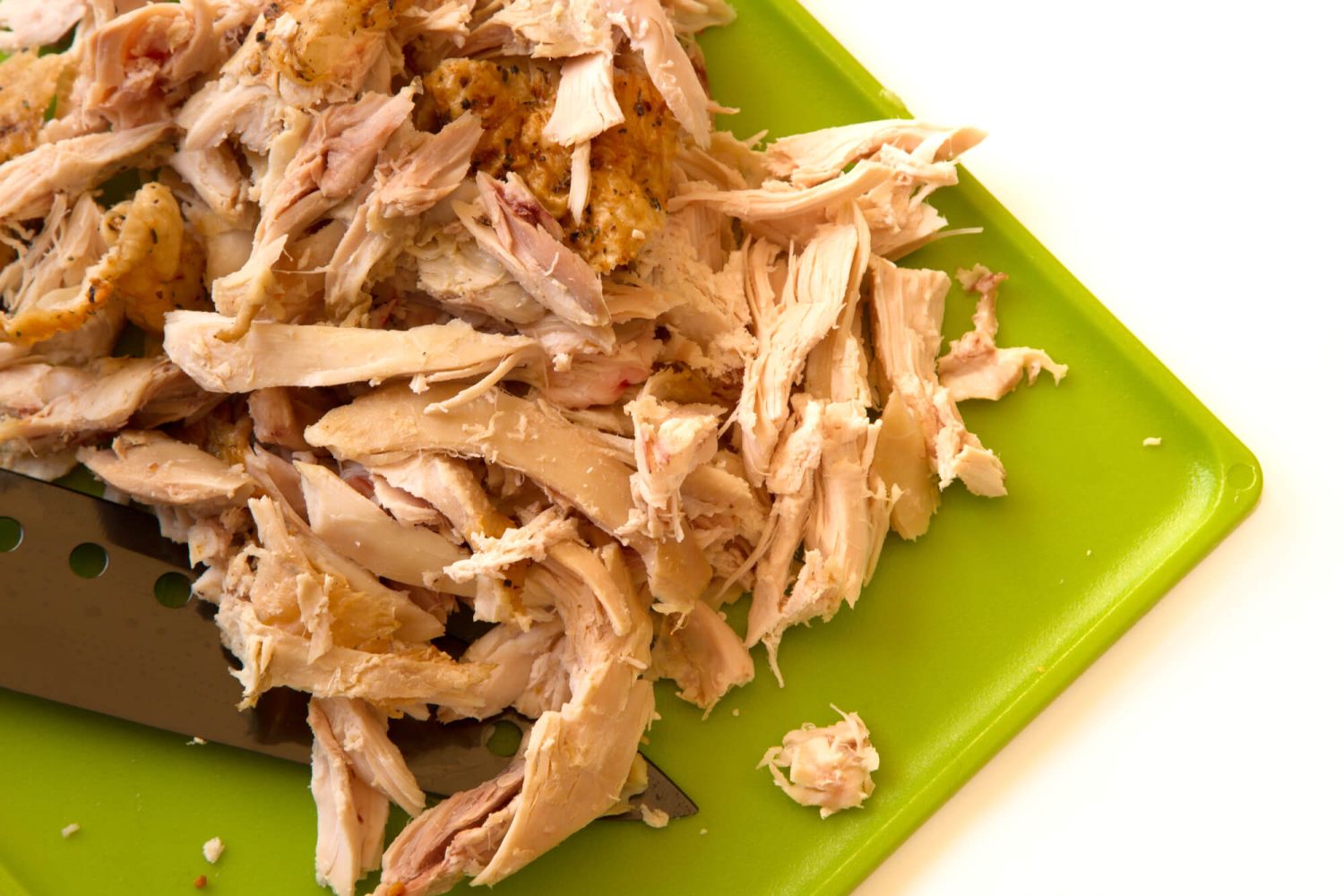 Shredded chicken on a cutting board for chicken enchilada casserole.