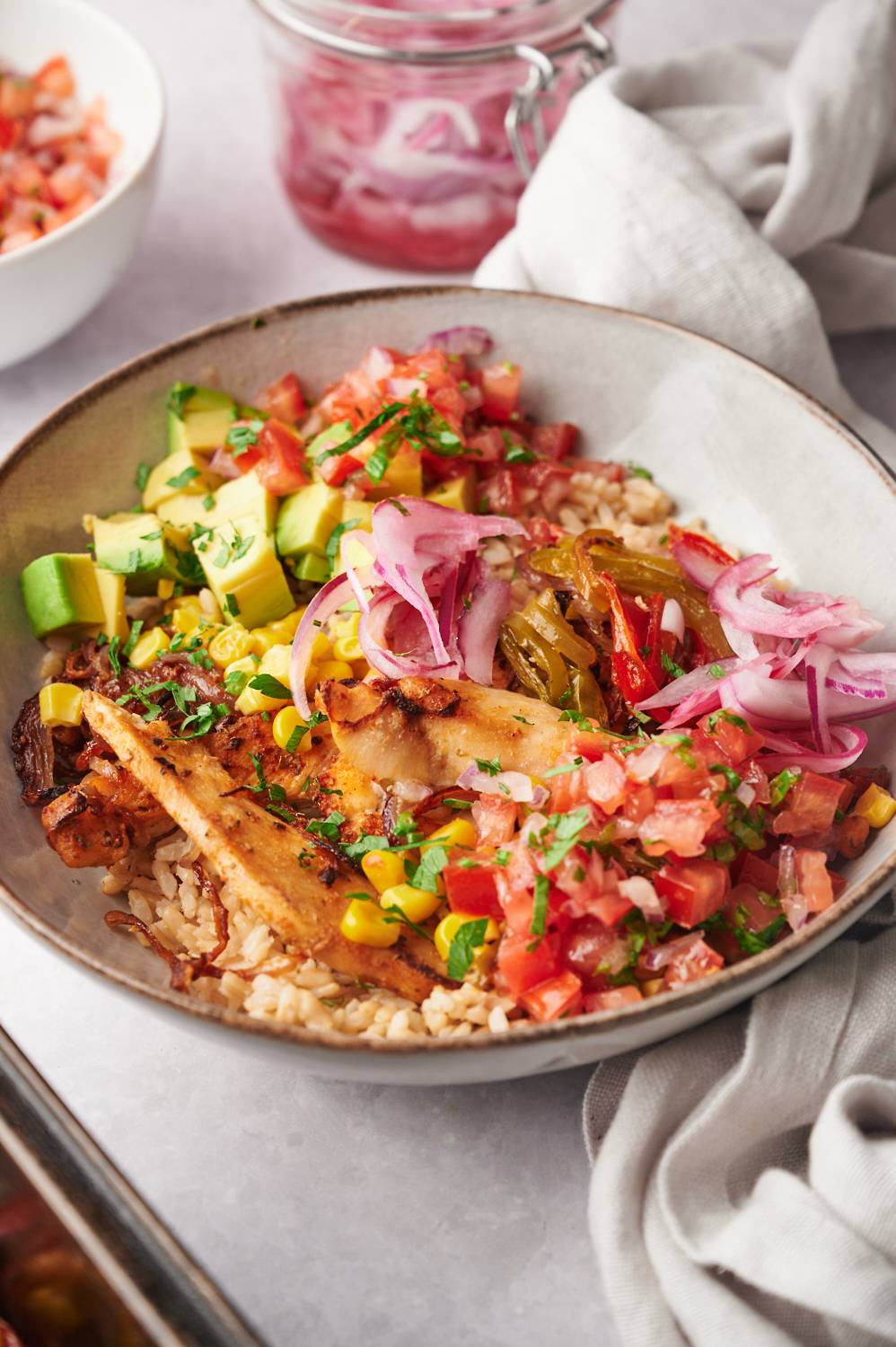 Fajita bowls with chicken breast, peppers, onions, corn, avocado, salsa, rice, and jalapenos. 