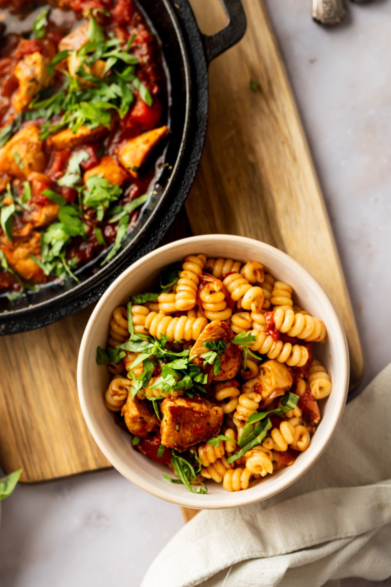 Pasta with chicken Fra Diavolo sauce served in a bowl with parsley and basil.