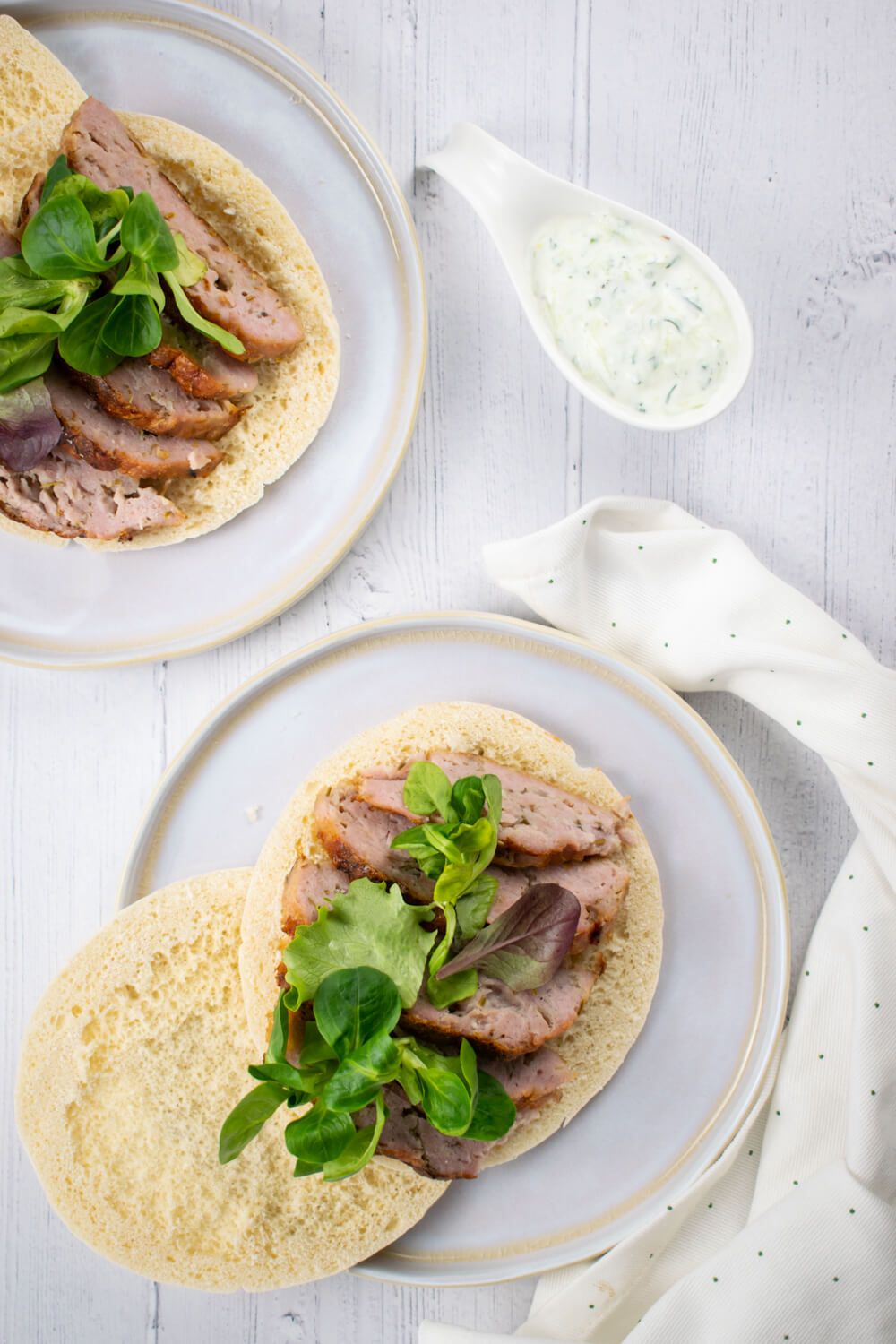 Chicken gyro meat sliced thin on pita bread with lettuce and tzatziki on the side.