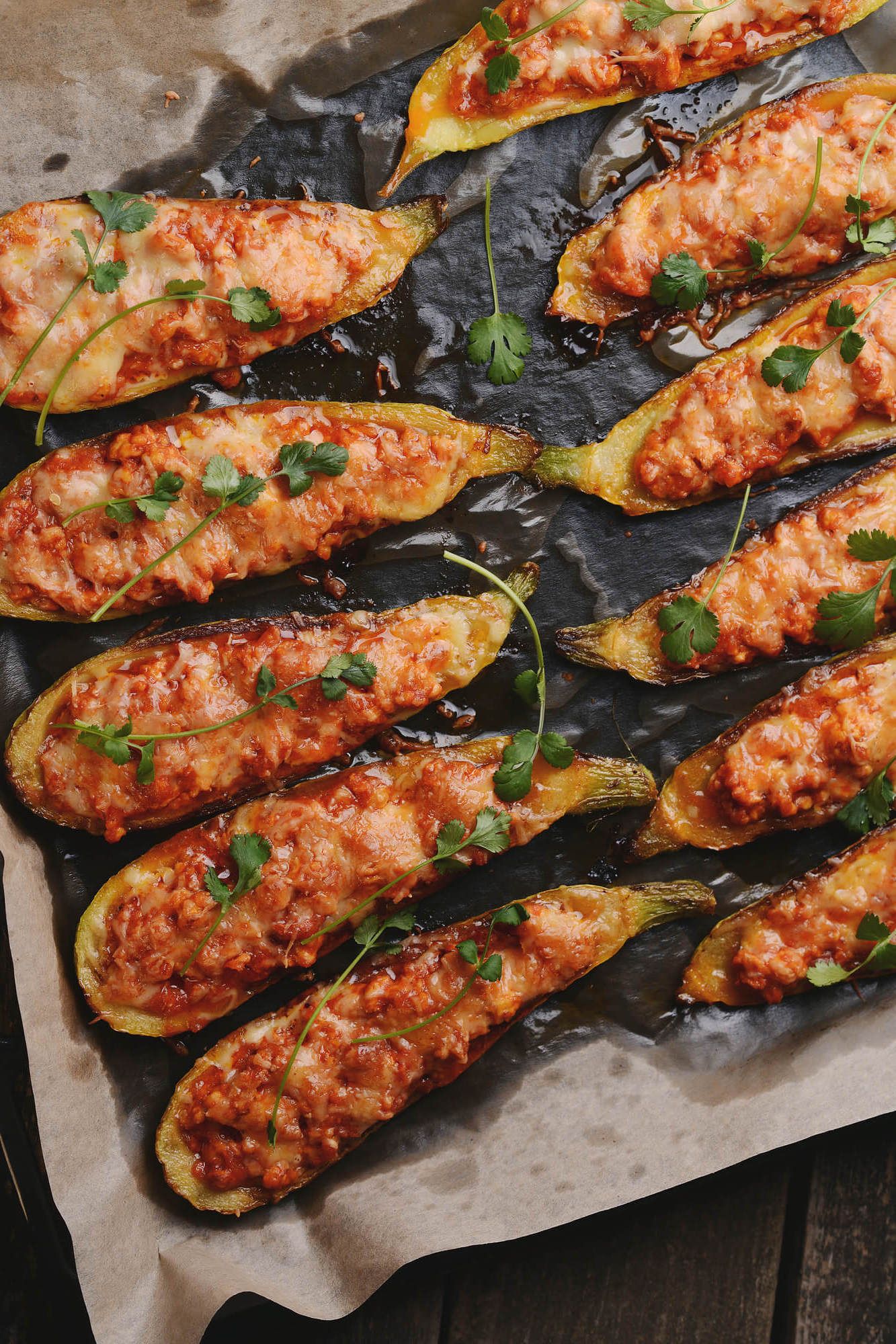 Zucchini boats with chicken, tomatoes, and melted cheese on a baking sheet.