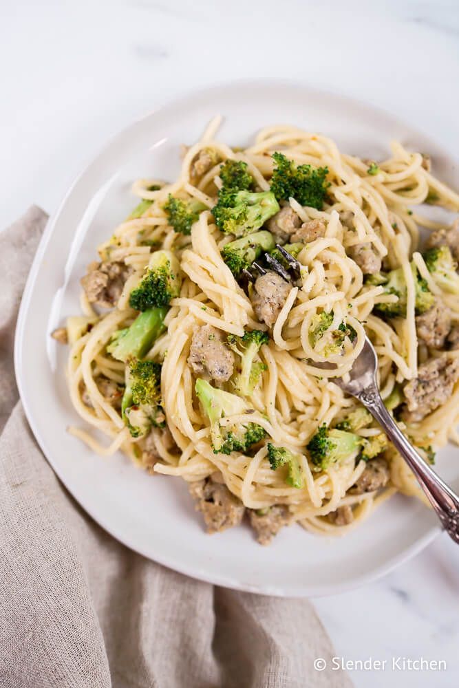 Pasta with chicken sausage and broccoli on a plate with parmesan cheese and spices.