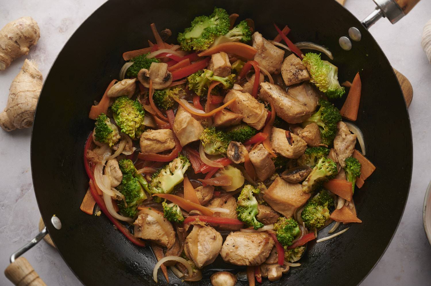 Wok with chicken stir fry with broccoli, bell peppers, mushrooms, and onion. 