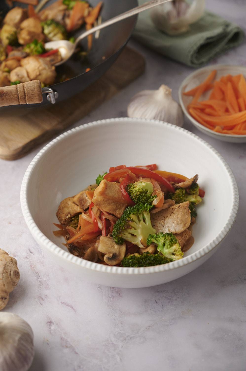 Chicken and vegetable stir fry with soy and honey sauce served in a white bowl.