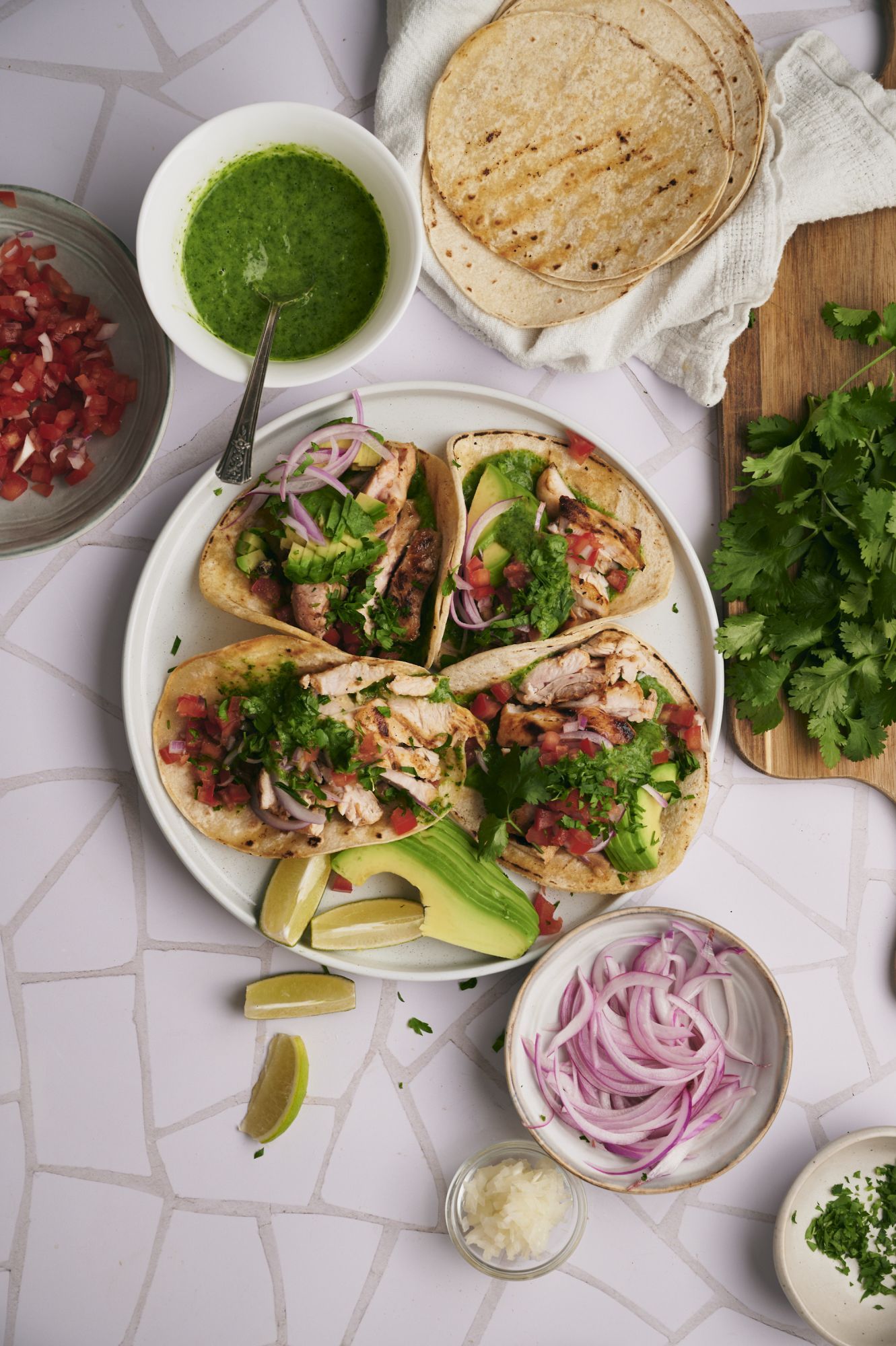 Street chicken tacos with grilled chicken, chopped cilantro, onions, avocado, and pico de gallo on tortillas.