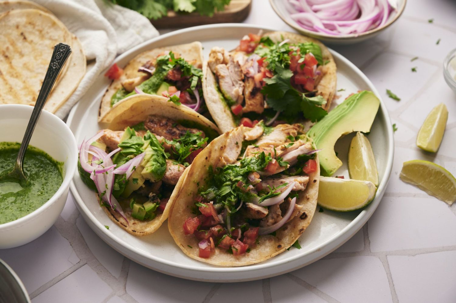 Street tacos with chicken, avocado, salsa, cilantro, and onion with salsa on the side. 