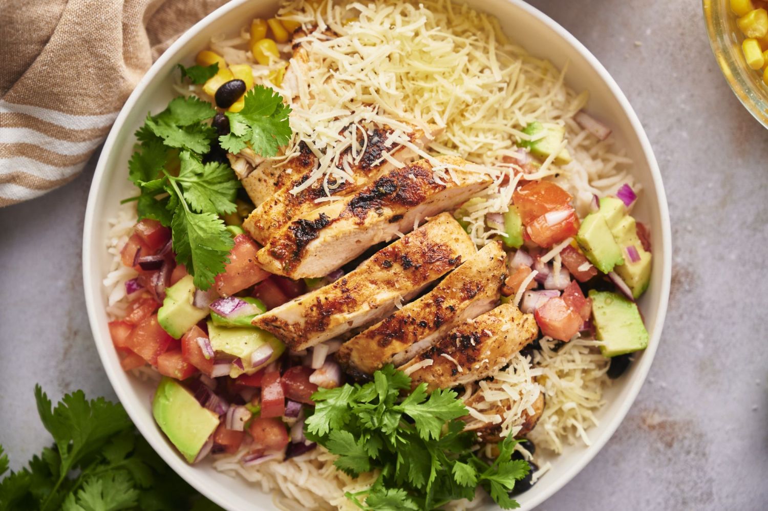 Chicken taco and rice bowl with cheese, cilantro, pico de gallo, avocado, corn, and black beans.