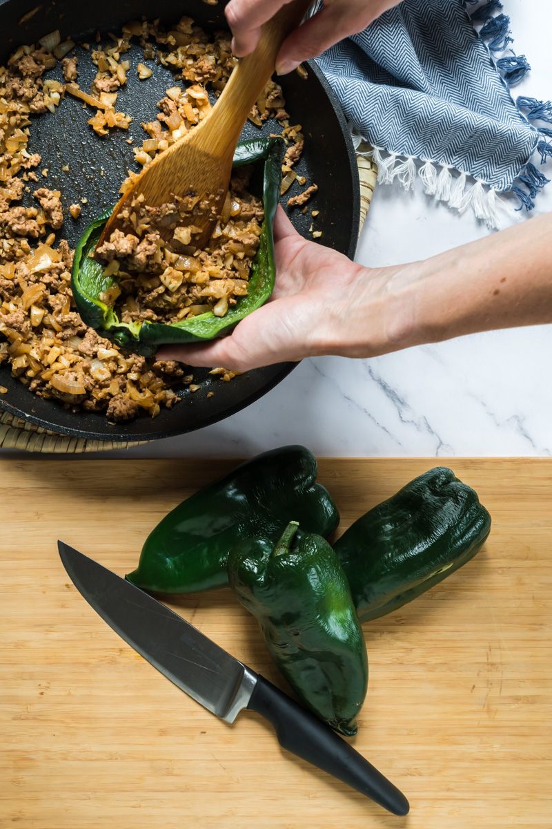 Stuffing roasted poblano peppers with ground turkey, cauliflower, and seasoning.