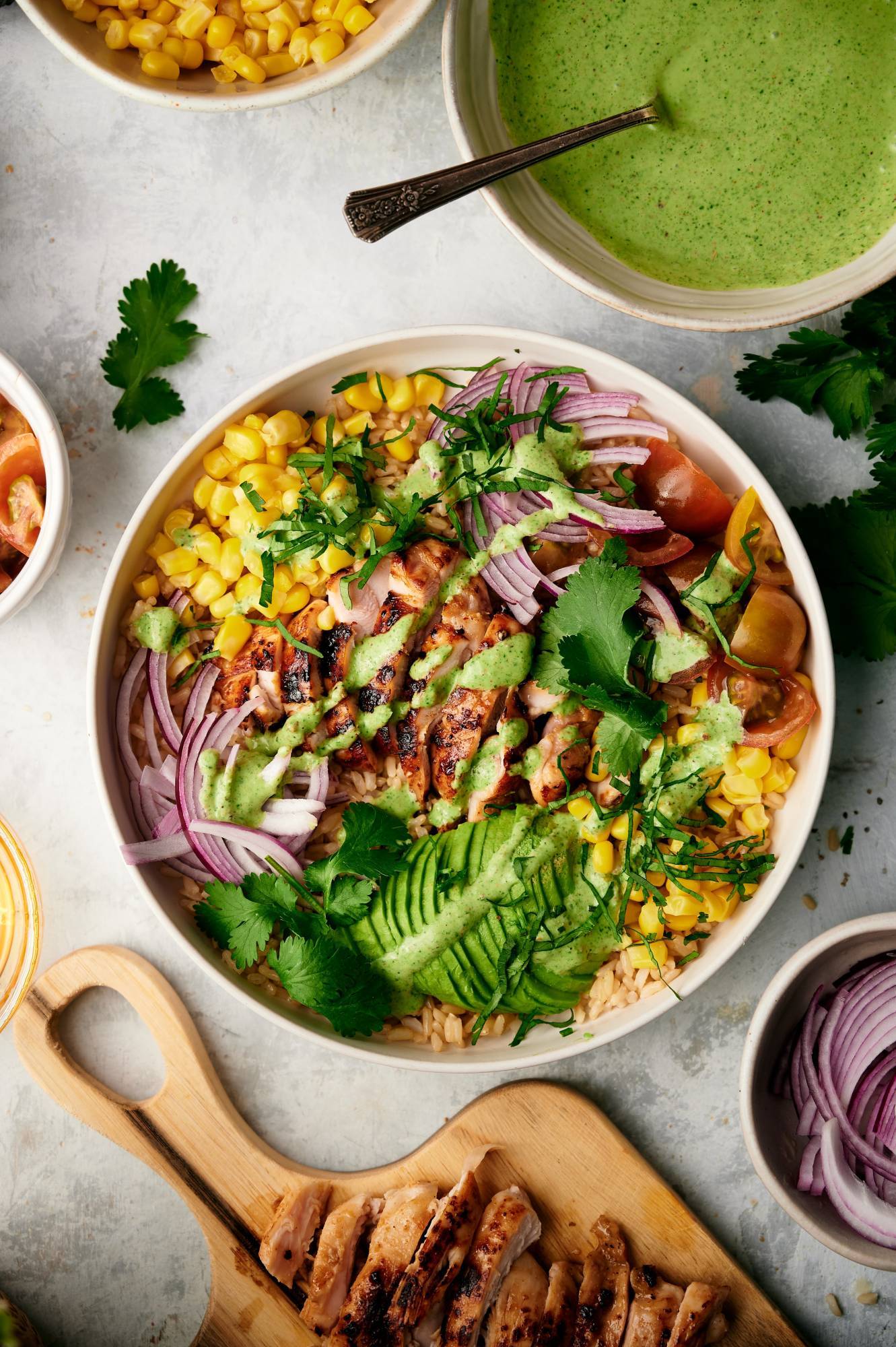 Grilled chicken bowl with avocado, cilantro, corn, tomatoes, and red onions with creamy cilantro lime sauce,