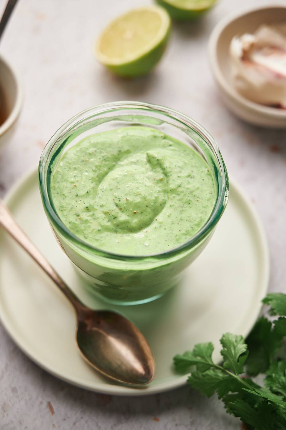 Creamy cilantro lime sauce with yogurt, fresh cilantro, lime juice, garlic, and spices in a glass jar.