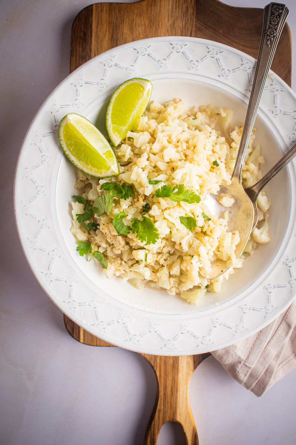 Cauliflower rice with coconut, cilantro, and lime in a bowl with two spoons.