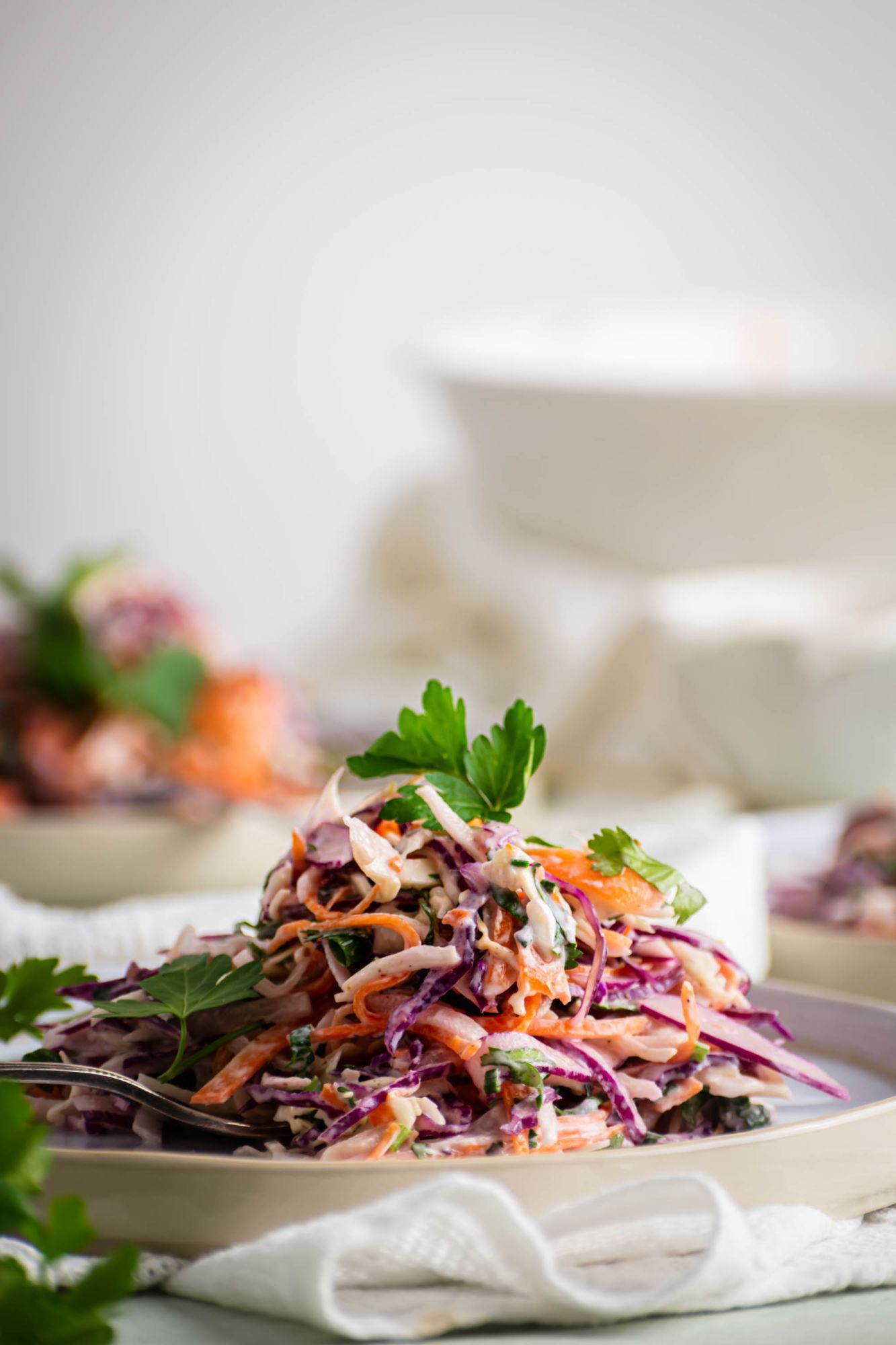 Greek yogurt coleslaw with shredded carrots, cabbage, and herbs on a plate.