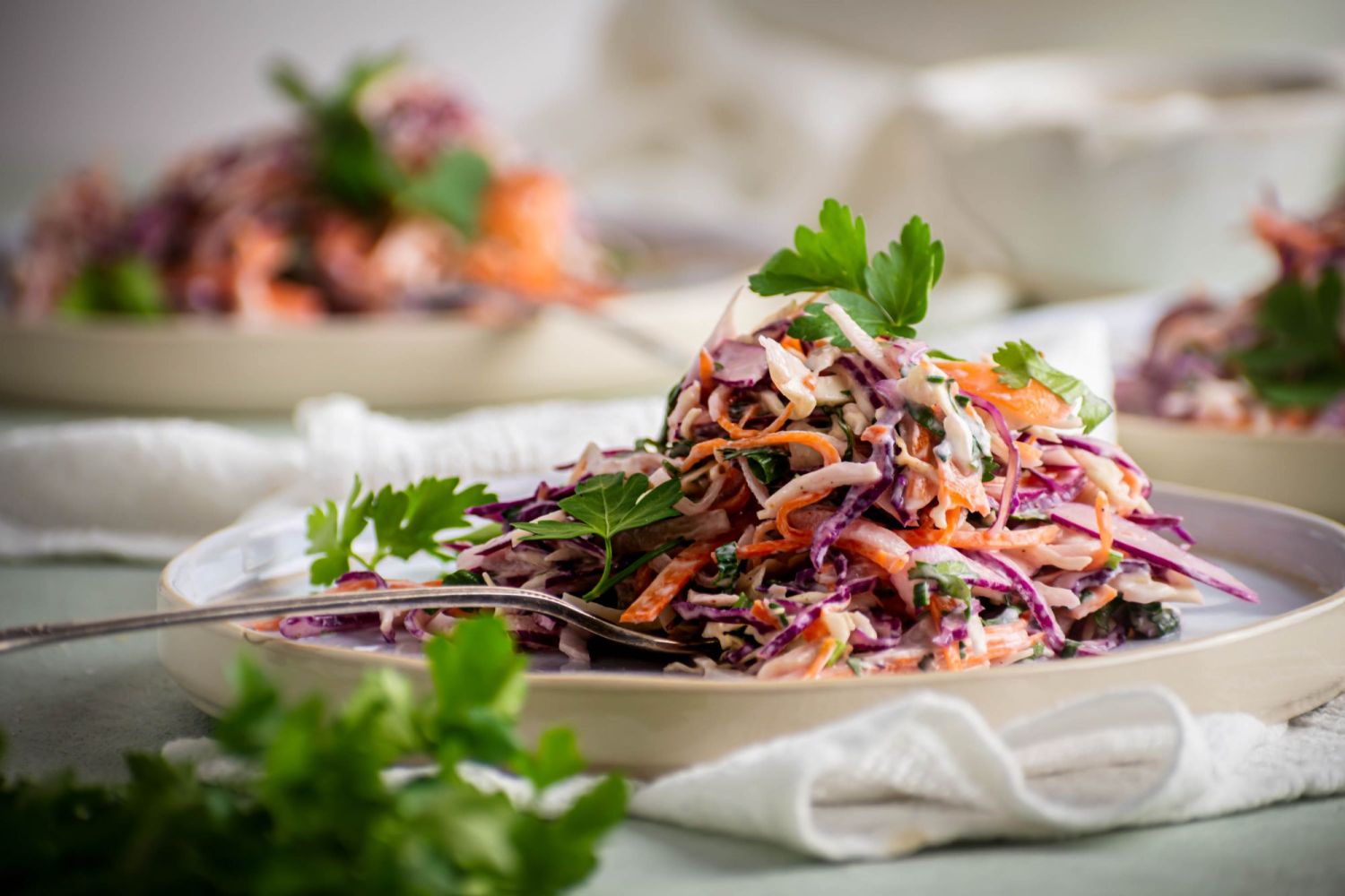 Shredded coleslaw with creamy yogurt dressing with fresh cilantro on a plate with a fork.