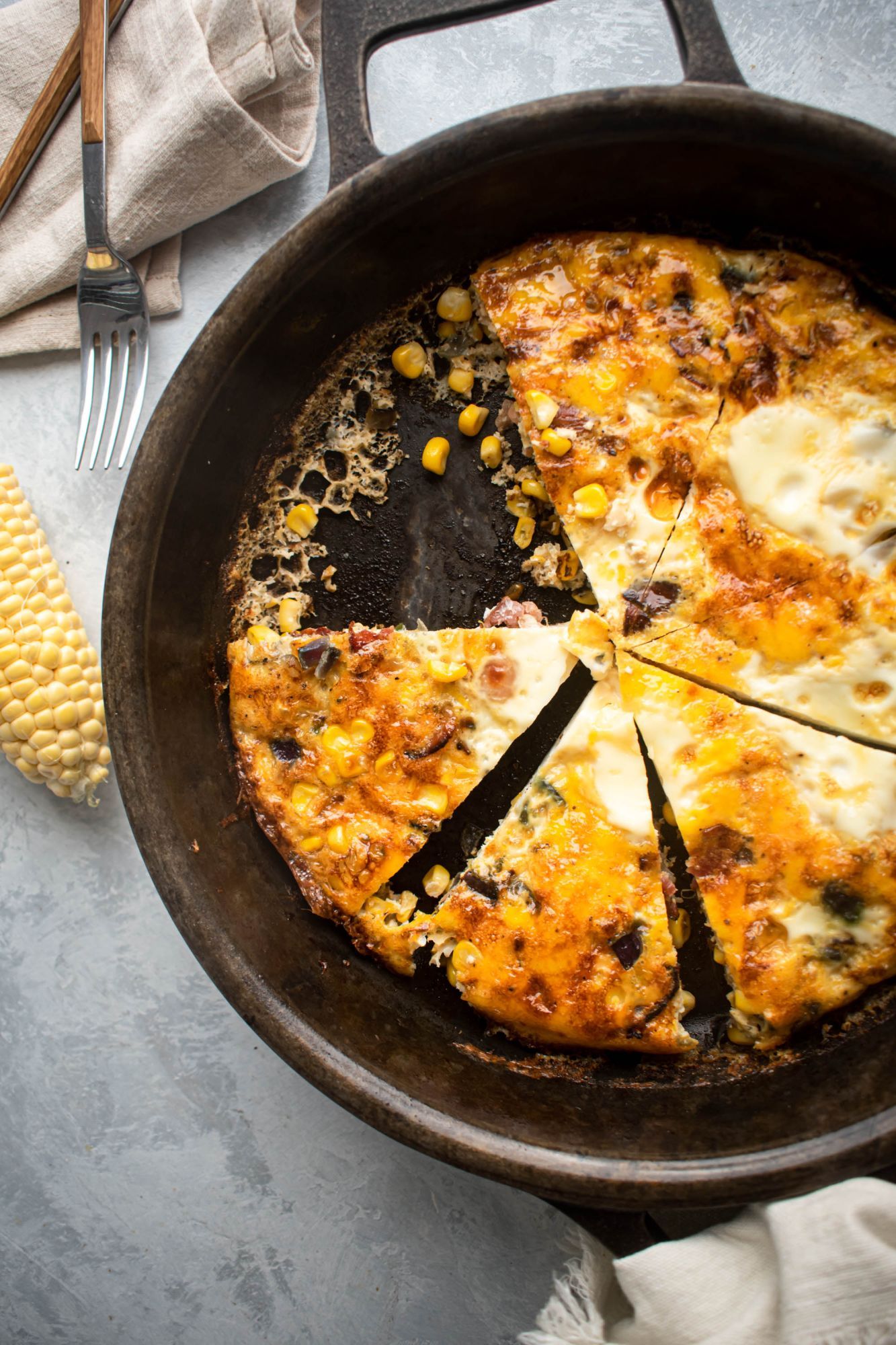 Corn bacon frittata in a cast iron skillet with fresh corn, onion, and jalapeno.