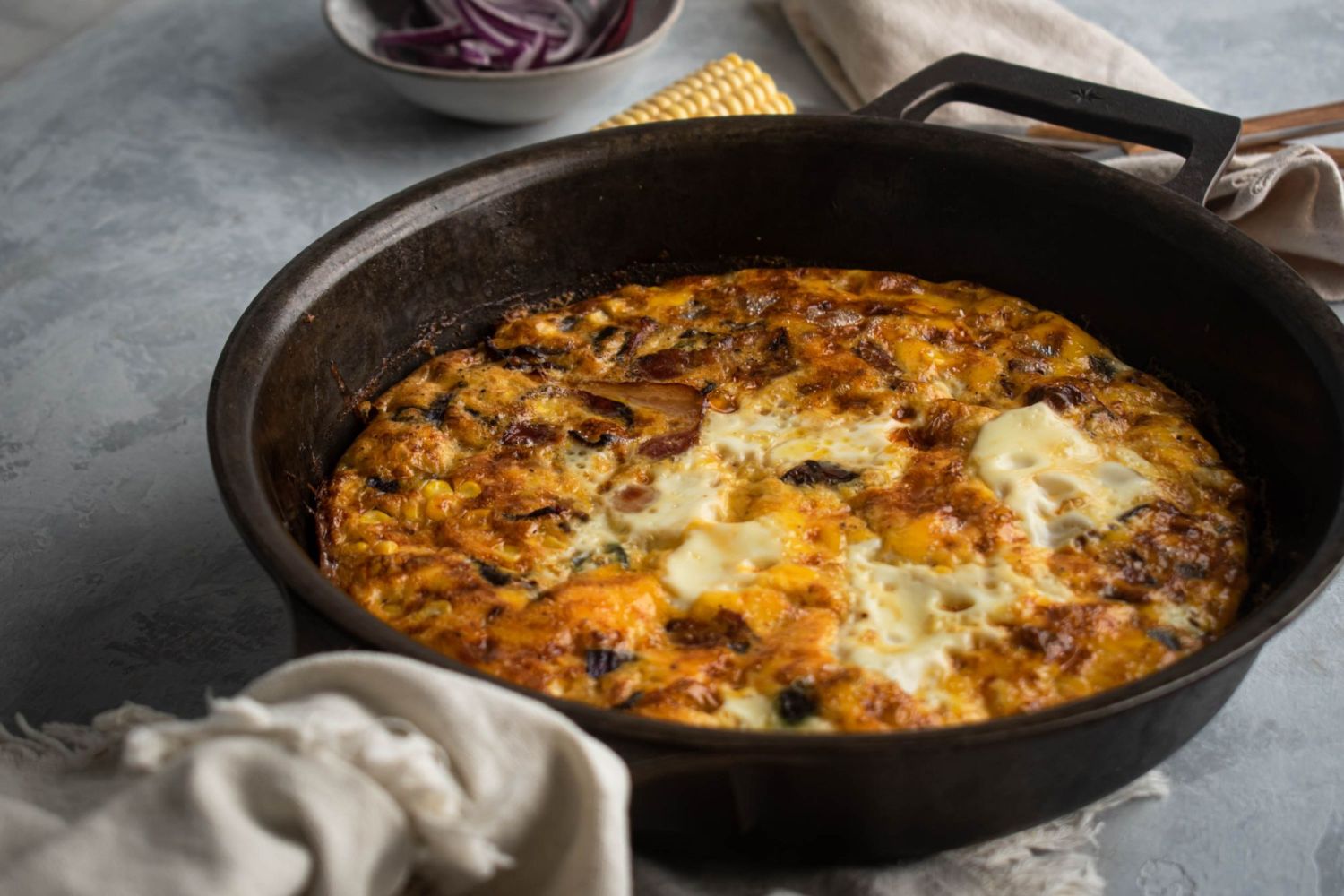 Caron, bacon, and jalapeno frittata with onion in a cast iron skillet. 