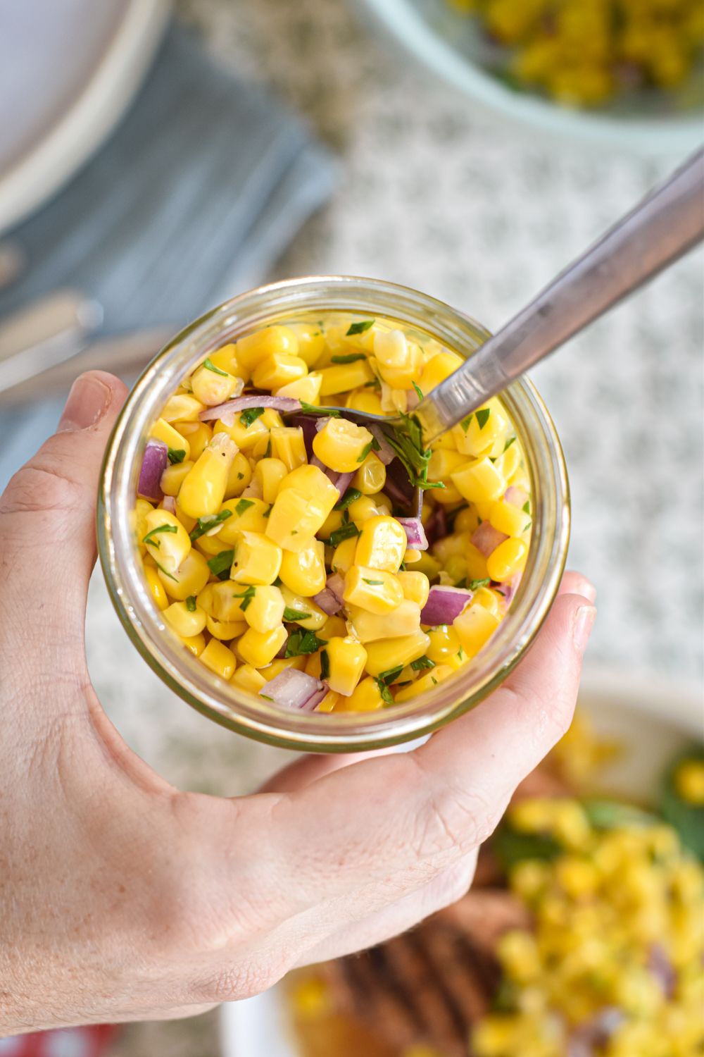 Chipotle corn salsa in a jar with red onion, lime juice, cilantro, and poblano pepper.