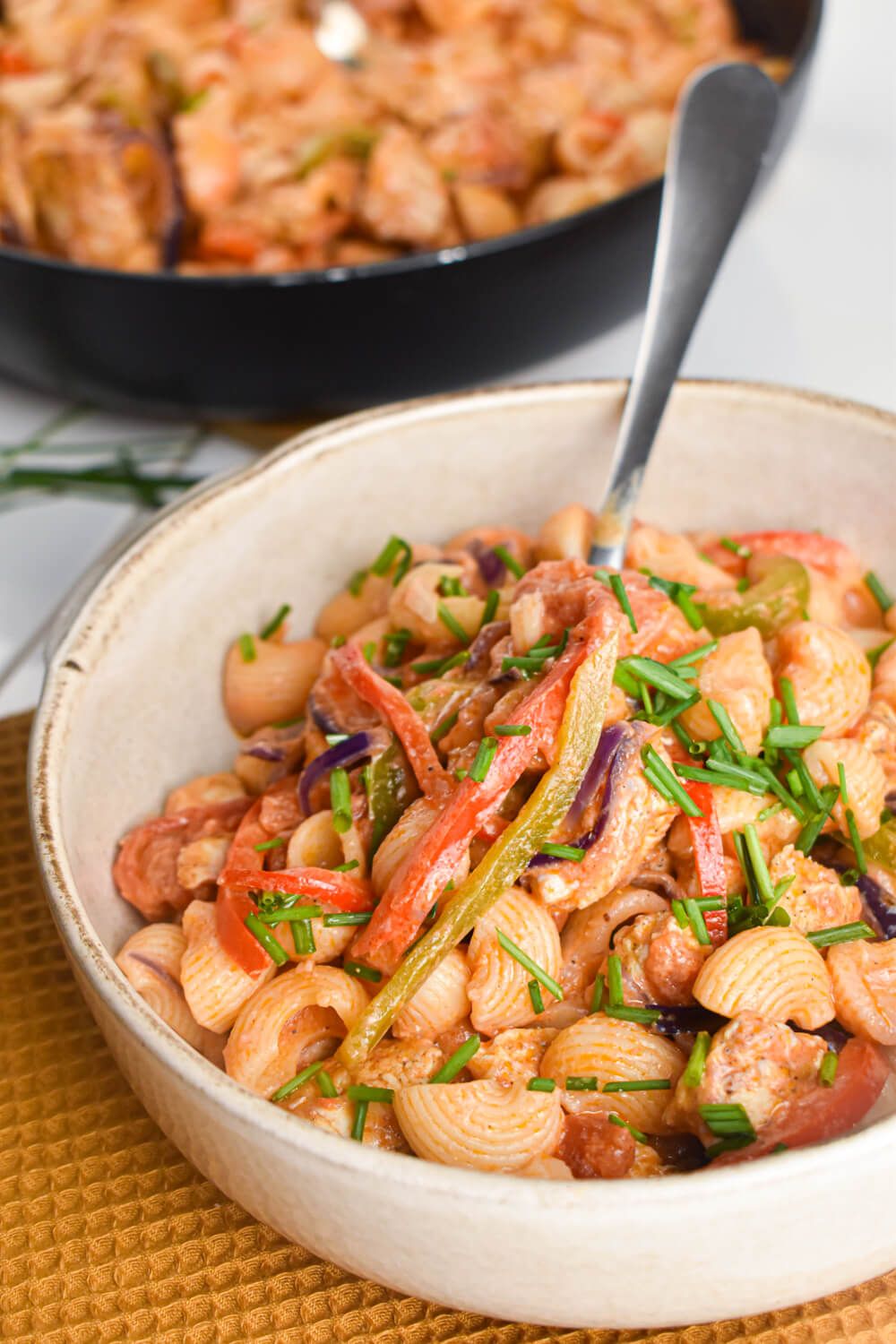 Chicken Cajun Pasta with bell peppers, onions, and a creamy tomato sauce in a bowl with green onions.