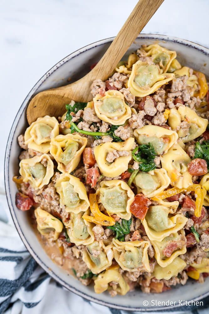 Chicken and spinach tortellini in tomato sauce with onions, peppers, and garlic in a bowl.