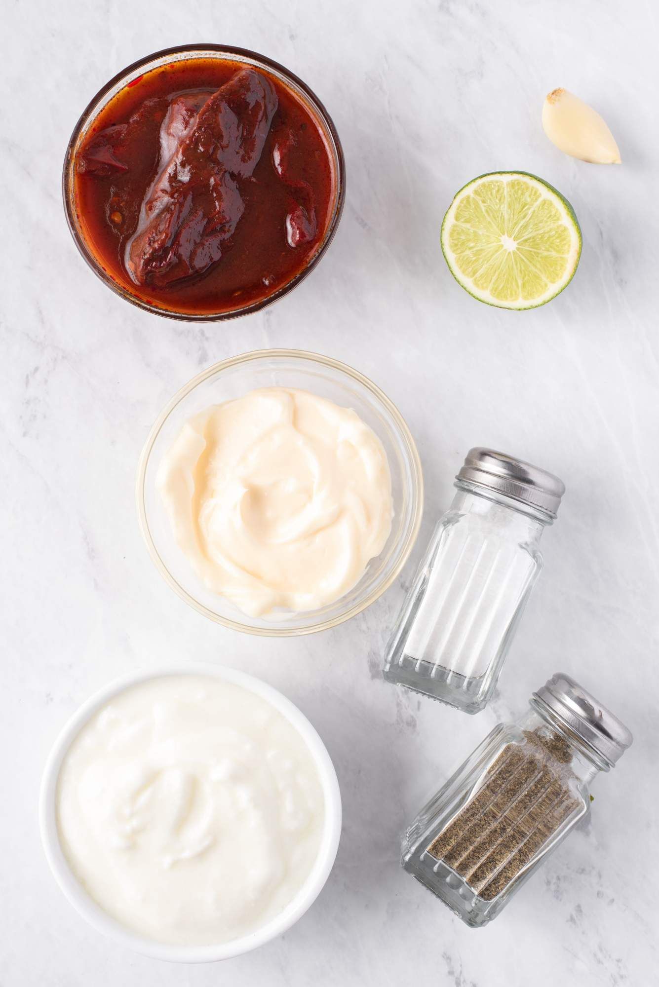 Ingredients for chipotle sauce including chipotle peppers, yogurt, mayo, garlic, and lime juice.