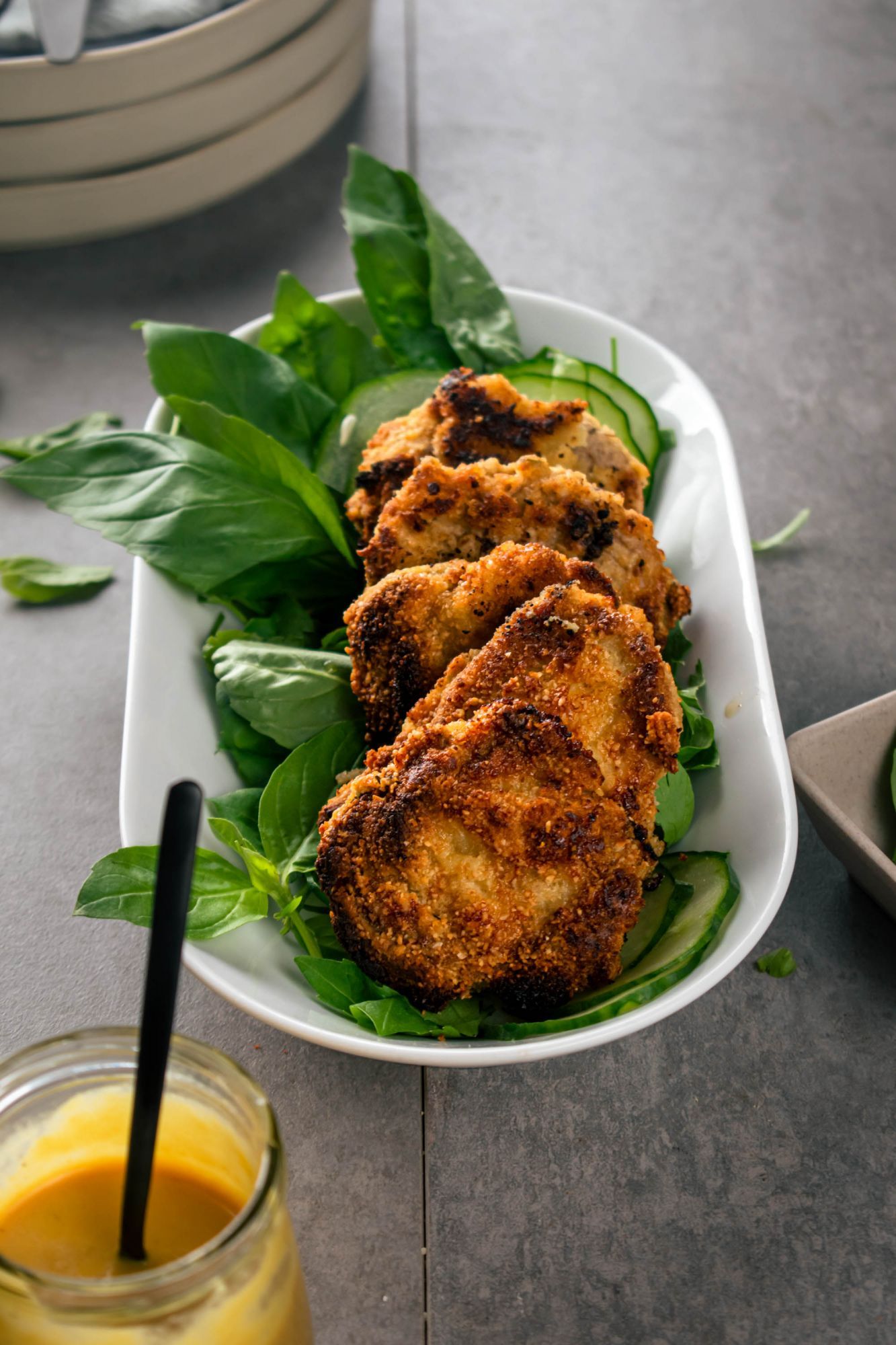 Low carb almond crusted pork chops with a crispy browned exterior on a bed of greens with mustard on the side.