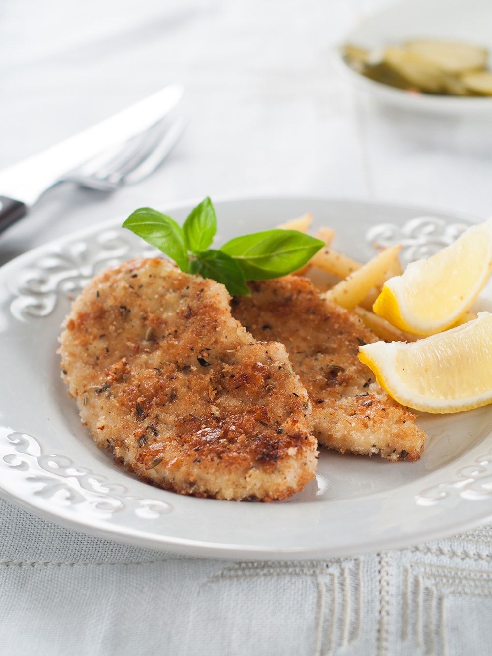 Crispy Baked Pork with lemon wedges on a white plate.