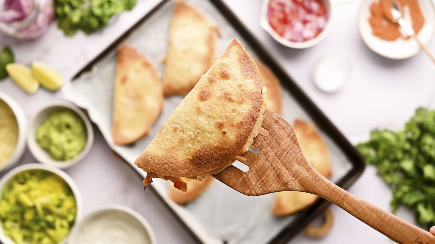 Baked crispy chicken taco being held up by a wooden spatula. 