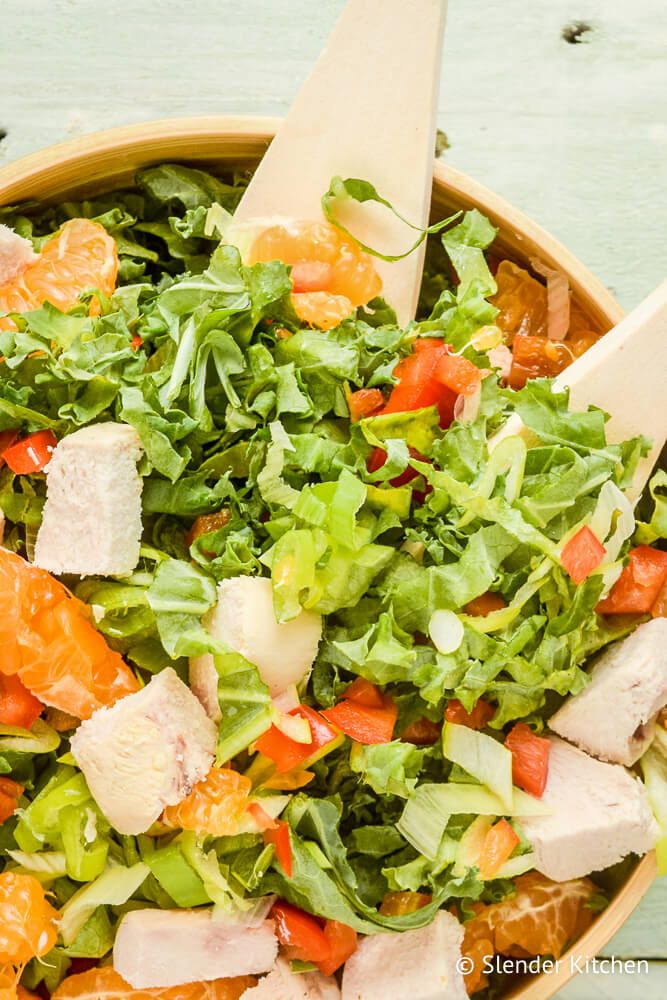 Chicken Mandarin Orange Salad in a bowl with lettuce, oranges, chicken, and sesame dressing.