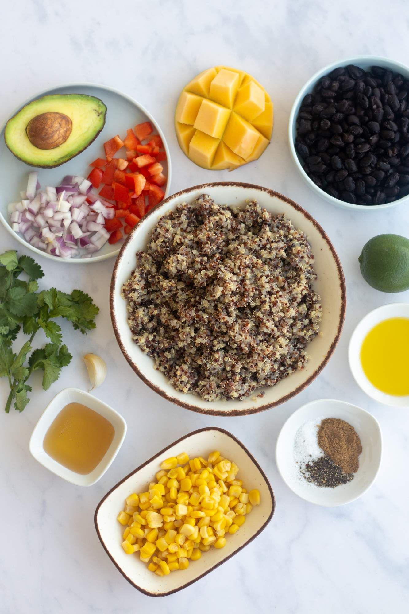 Ingredients for Cuban Black Bean Bowls including quinoa, canned black beans, mango, red peppers, corn, and honey lime dressing.