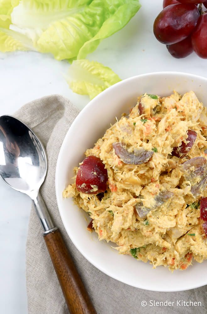 Curried tuna salad in a bowl with red grapes and lettuce on the side.