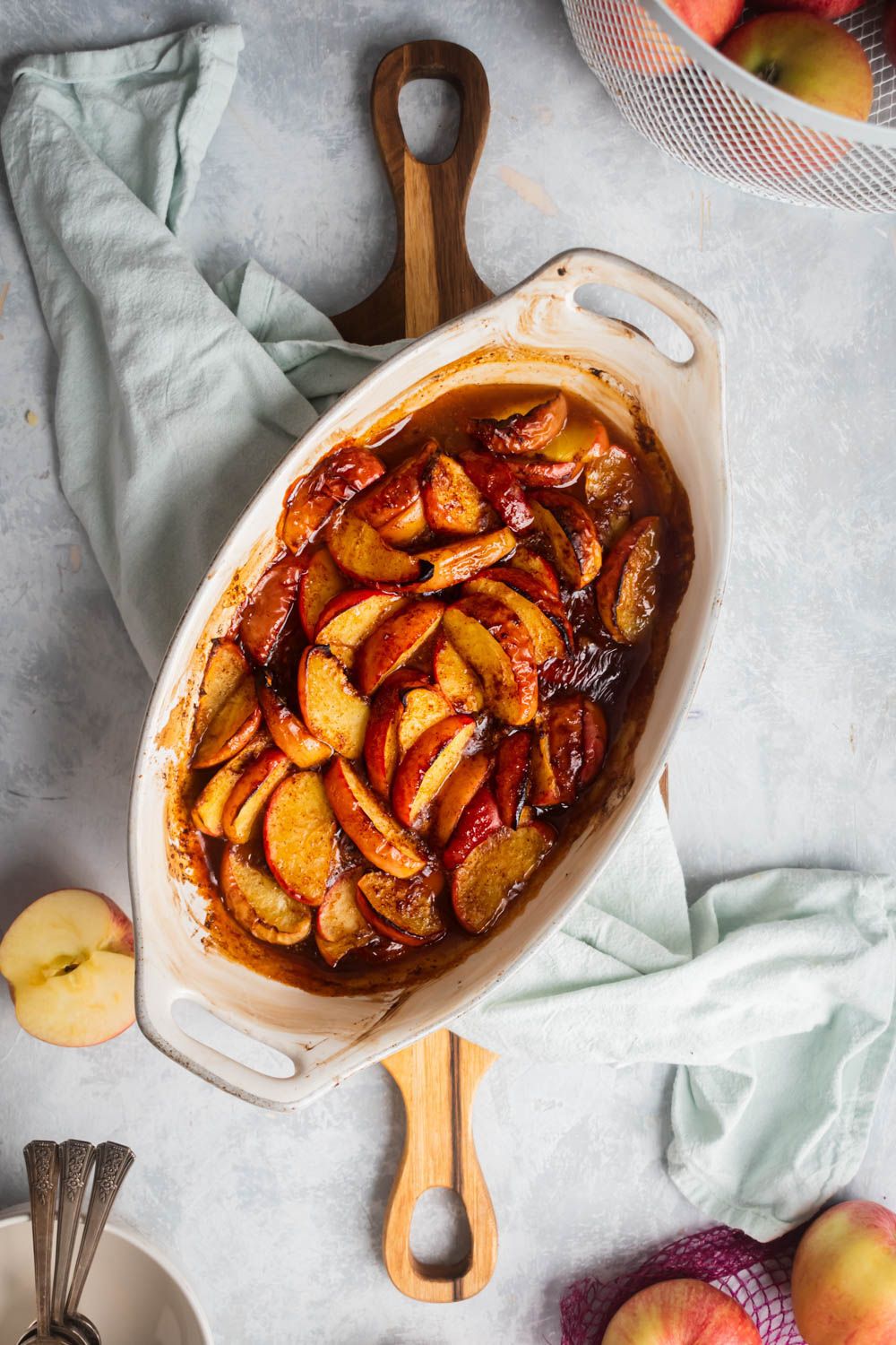 Cinnamon baked apples in a baking dish with maple syrup, lemon juice, cinnamon, and sliced apples.