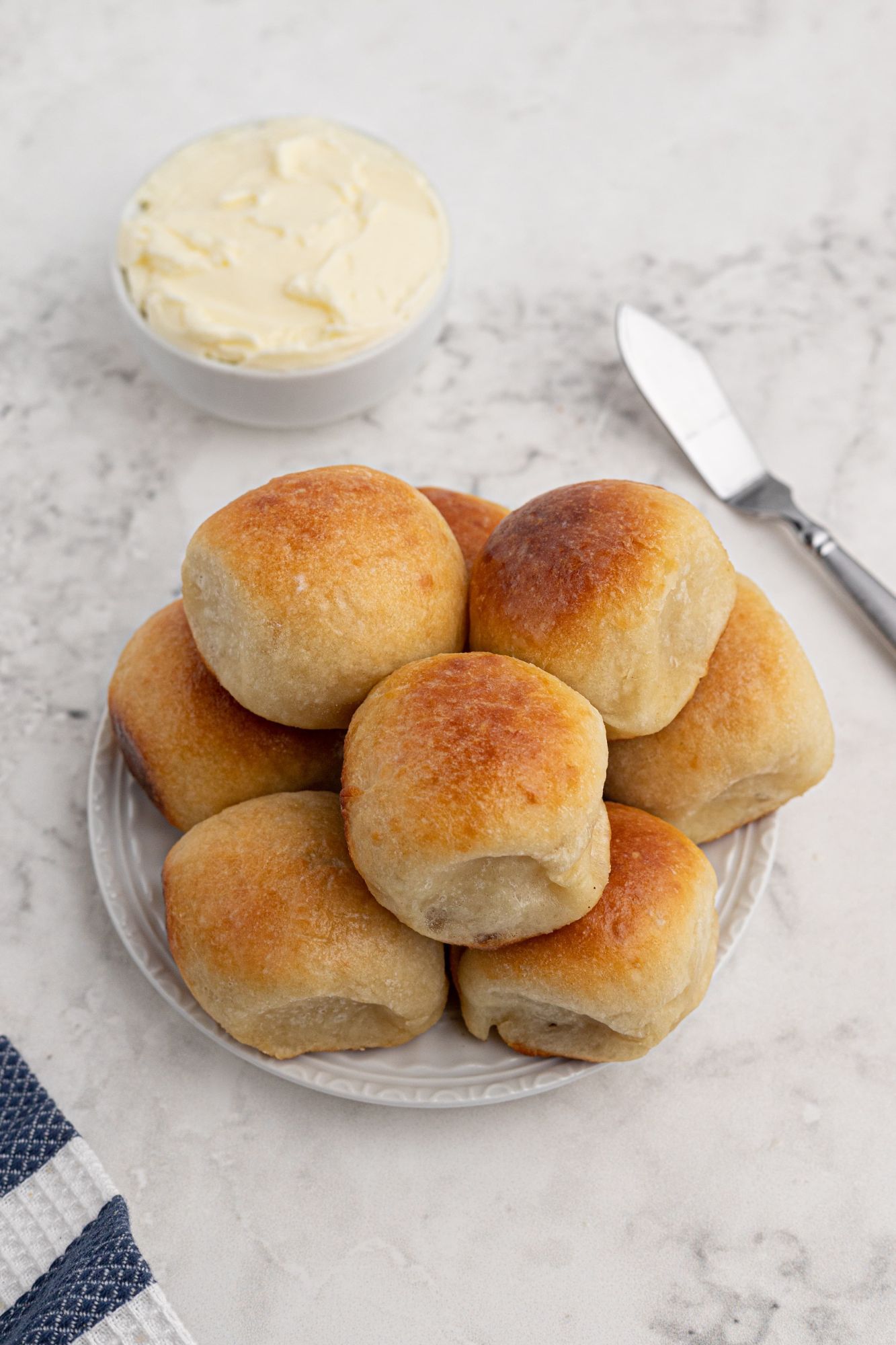 Golden brown dinner rolls made with Greek yogurt dough on a plate with a blue napkin.