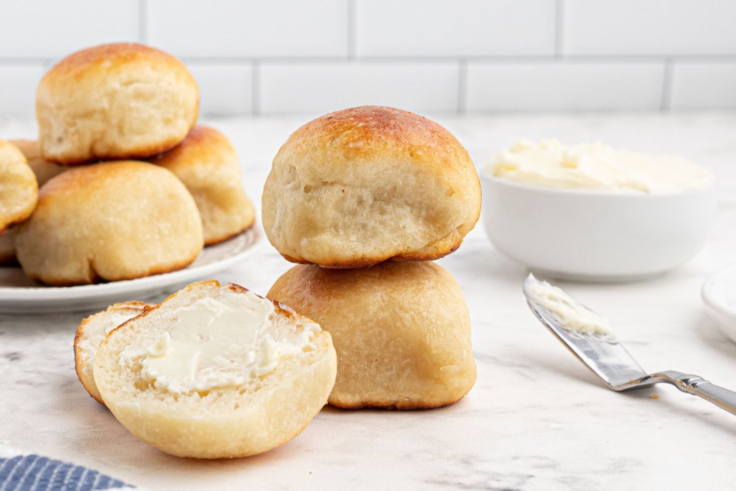 Two ingredient dough dinner rolls with butter on the side on a knife.