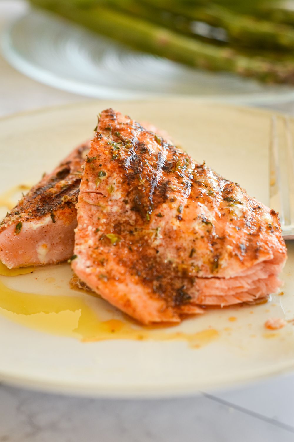 Salmon that was cooked on the grill with Cajun seasoning on a plate with asparagus.