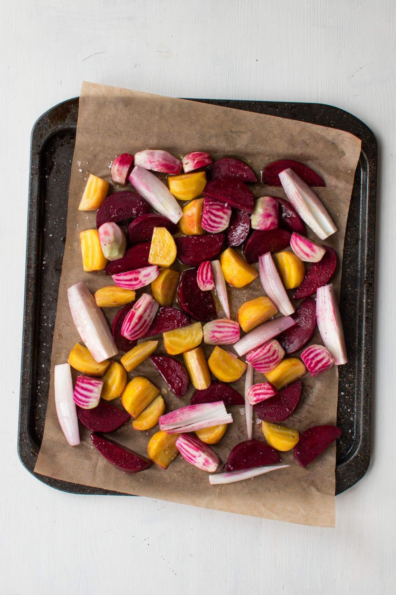 Beets before being roasted on a baking sheet with parchment paper.