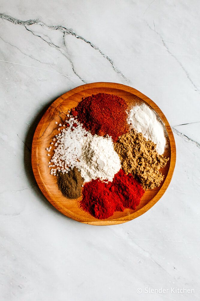 Fajita spice blend ingredients in small wooden bowls including paprika, chili powder, garlic powder, onion powder, salt, and pepper.