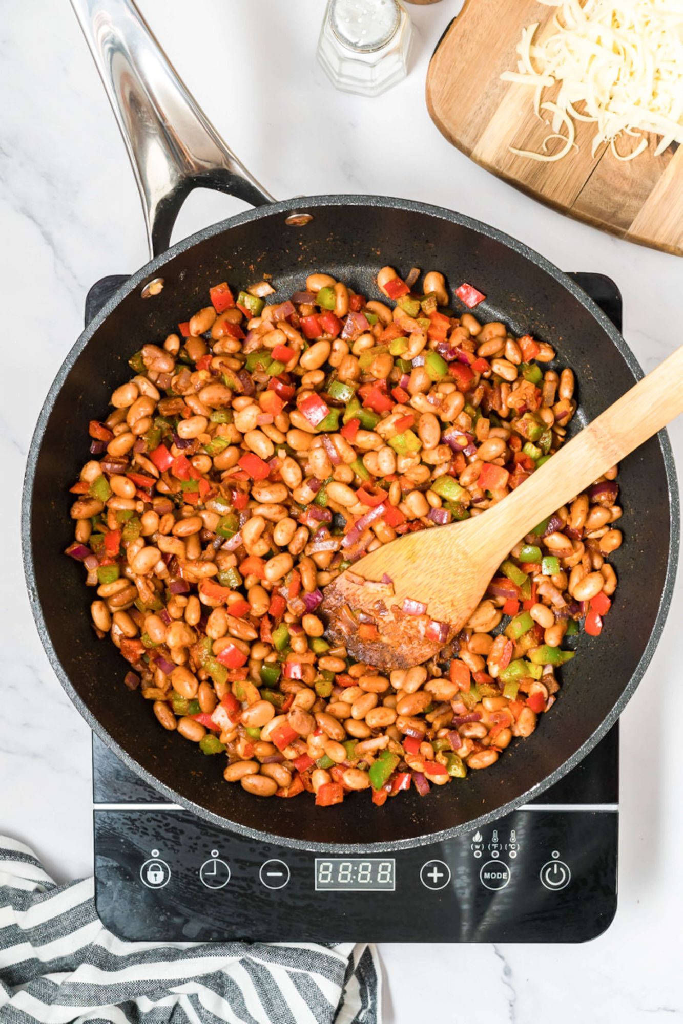 Pinto beans, peppers, onions, and fajita seasoning cooking in a skillet for zucchini boats.