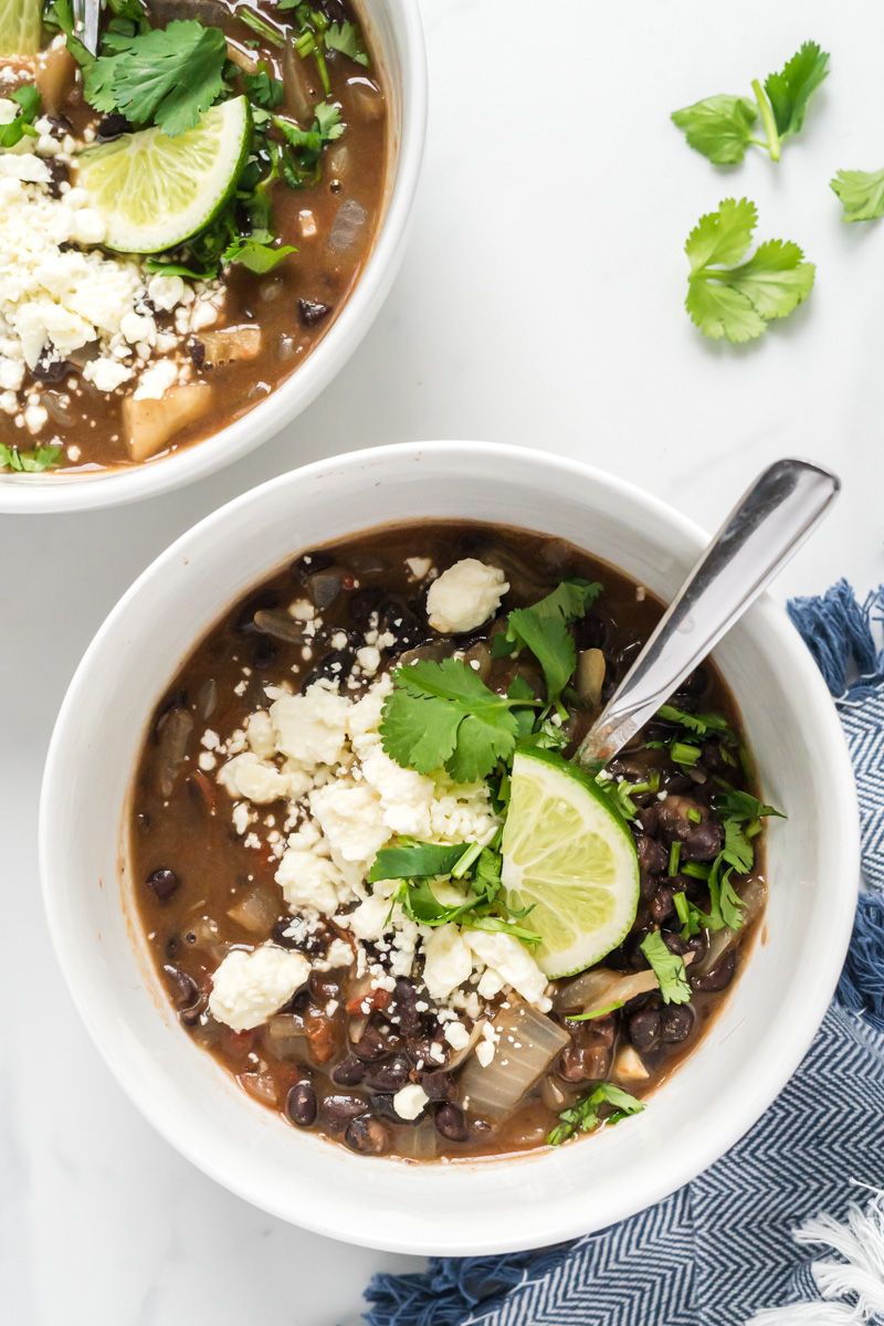 Bean soup made with black beans, tomatoes, and onions topped with cilantro, lime, and queso fresco.