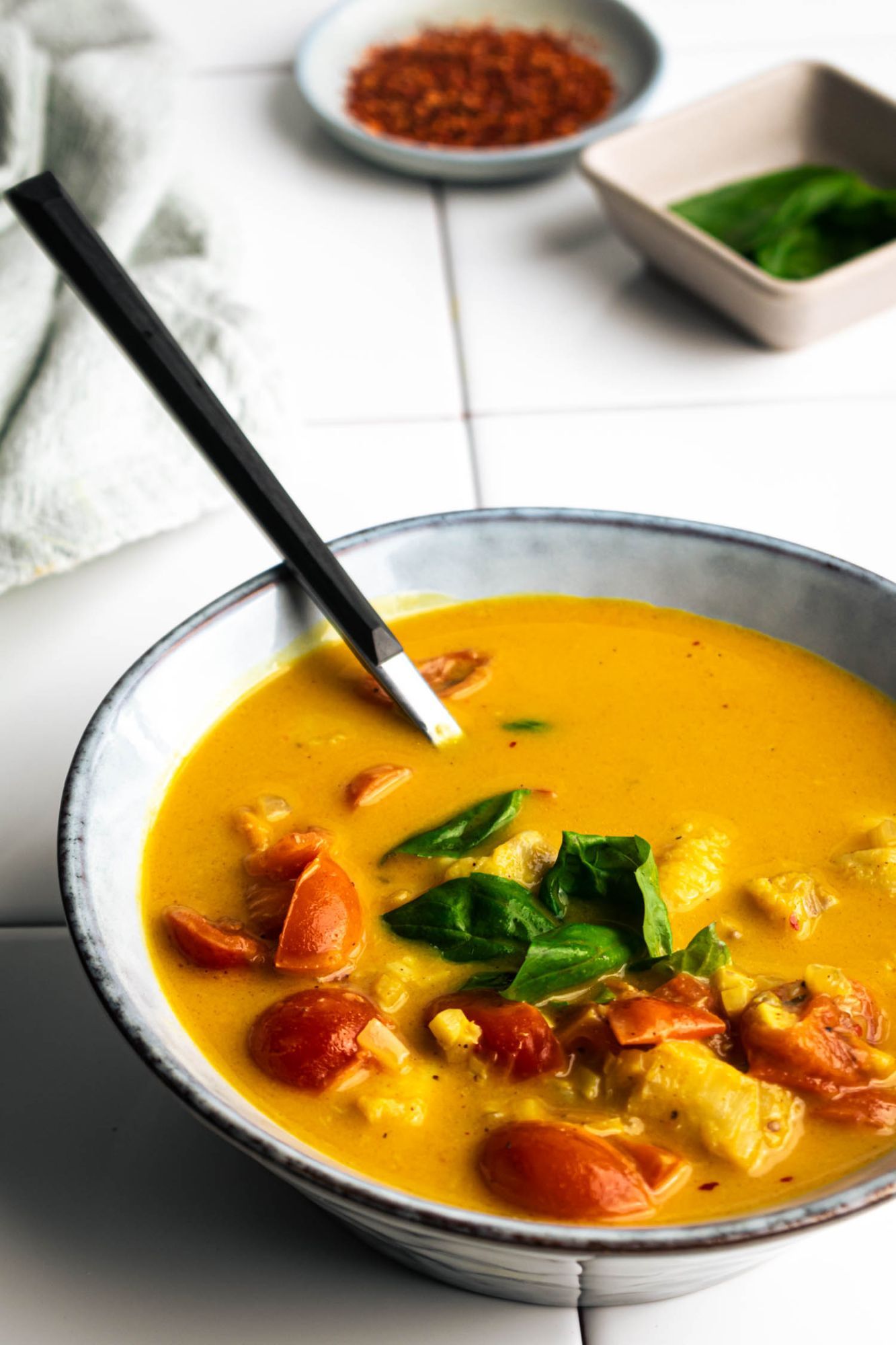 Coconut fish curry with white fish, tomatoes, curry powder, garlic, and ginger in a creamy coconut broth served in a blue bowl.