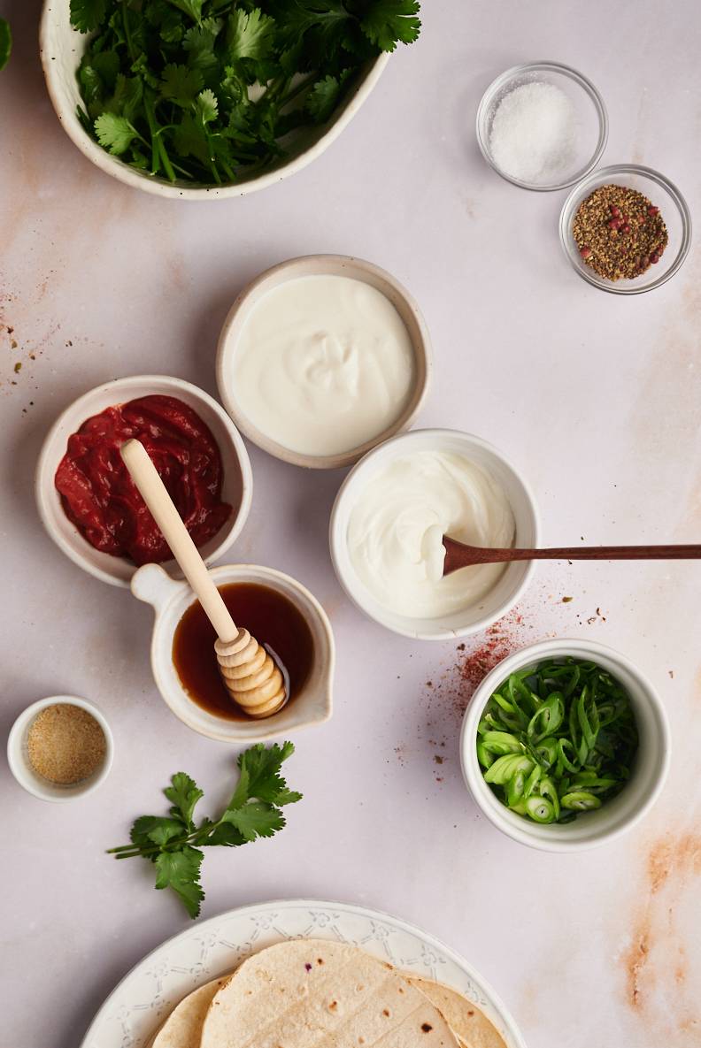 Ingredients for fish taco sauce including Mexican crema, Greek yogurt, chipotle peppers, limes, salt, and peppers.