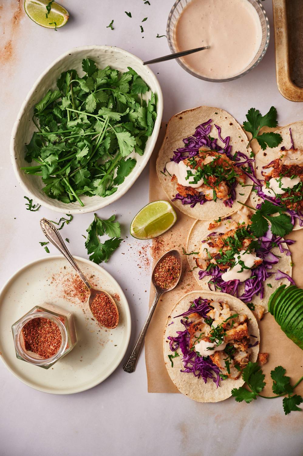 Fish tacos with homemade seasoning blend served with cabbage, cilantro, fish taco sauce, and extra spice rub.