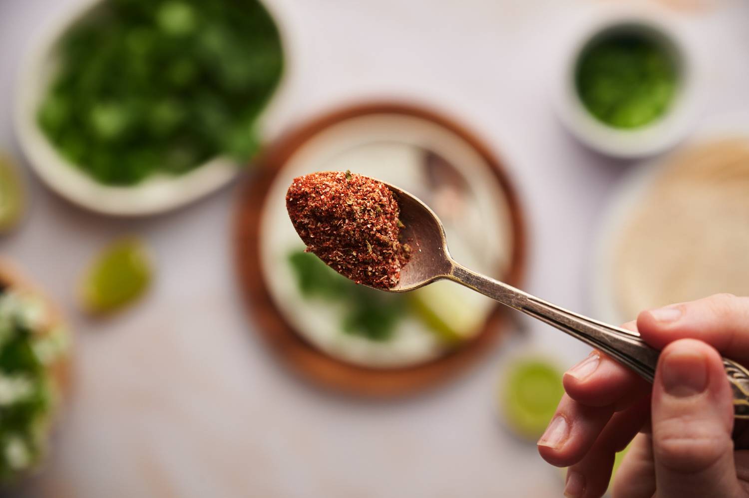 Taco seasoning for fish tacos with paprika, chili powder, garlic powder, onion powder, and oregano in a spoon.