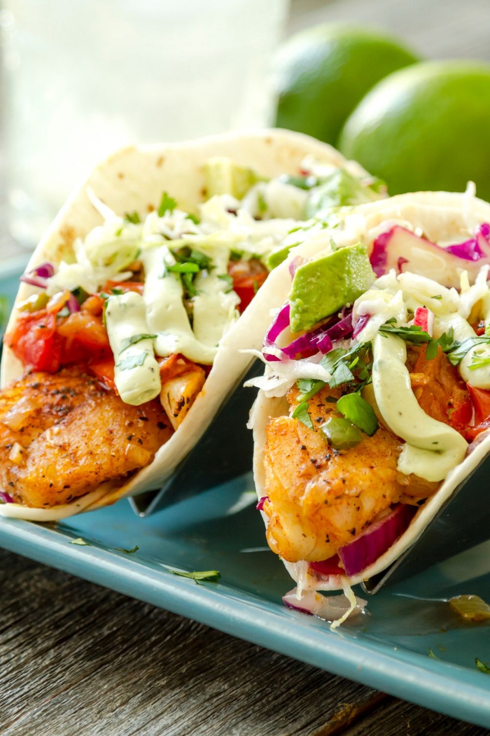 Fish tacos with a homemade spice mix with avocado on top and cabbage on corn tortillas