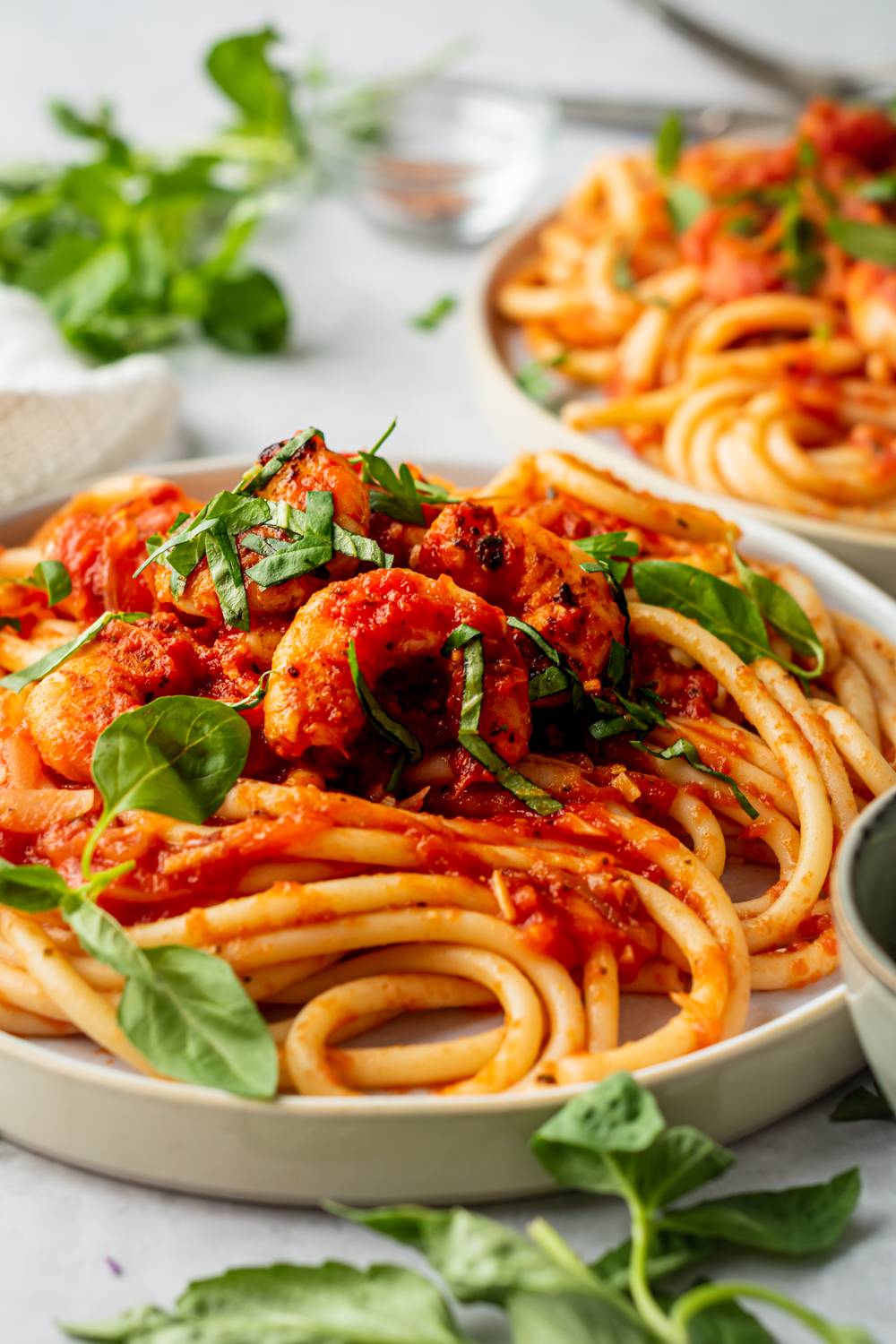 Shrimp fra diavolo with spicy tomato sauce and pasta served on a plate with fresh basil.