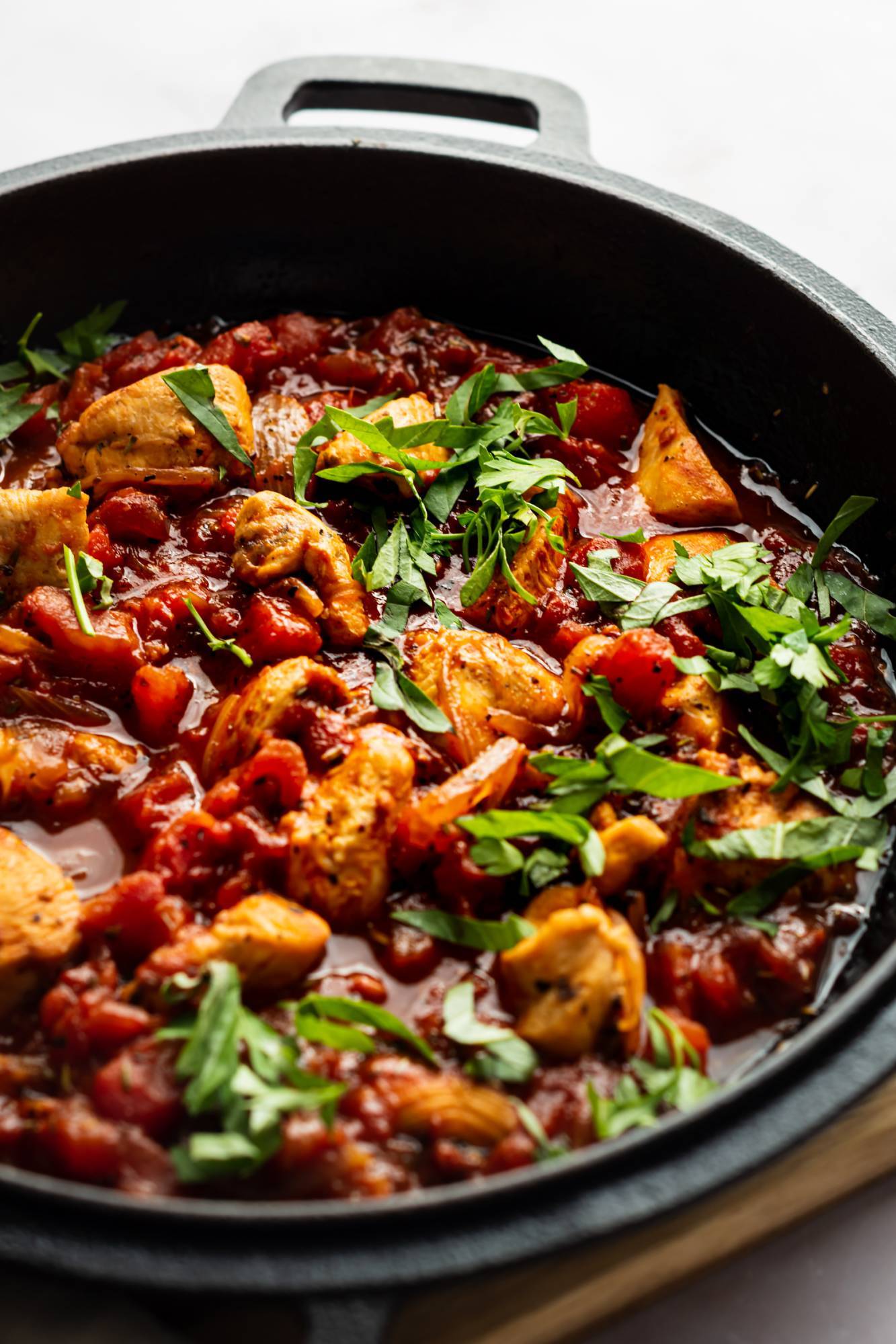 Chicken fra diavolo sauce served in a cast iron skillet with fresh herbs.