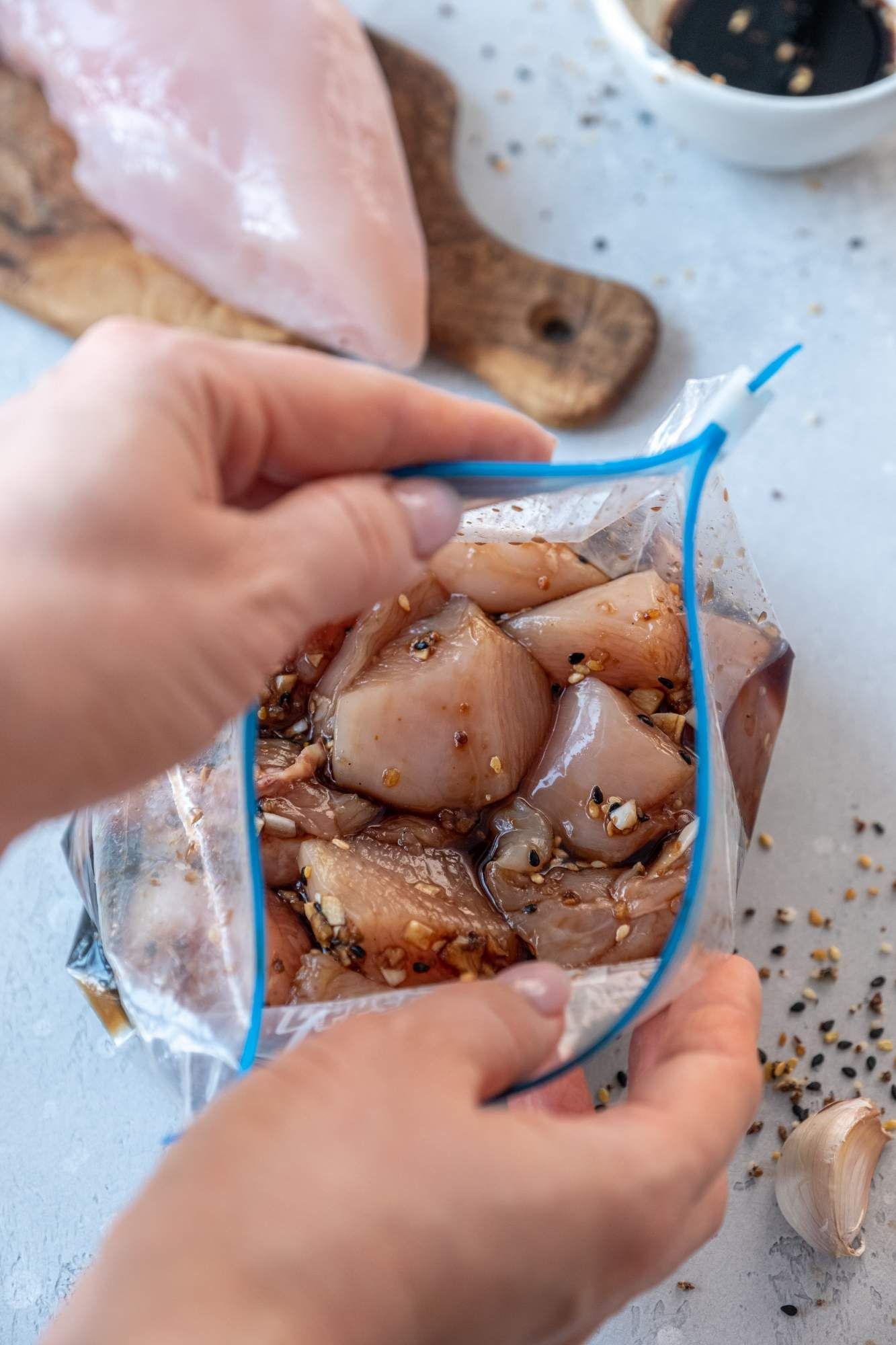 Chicken freezer meal being placed into a Ziploc bag with teriyaki sauce and chicken breast.