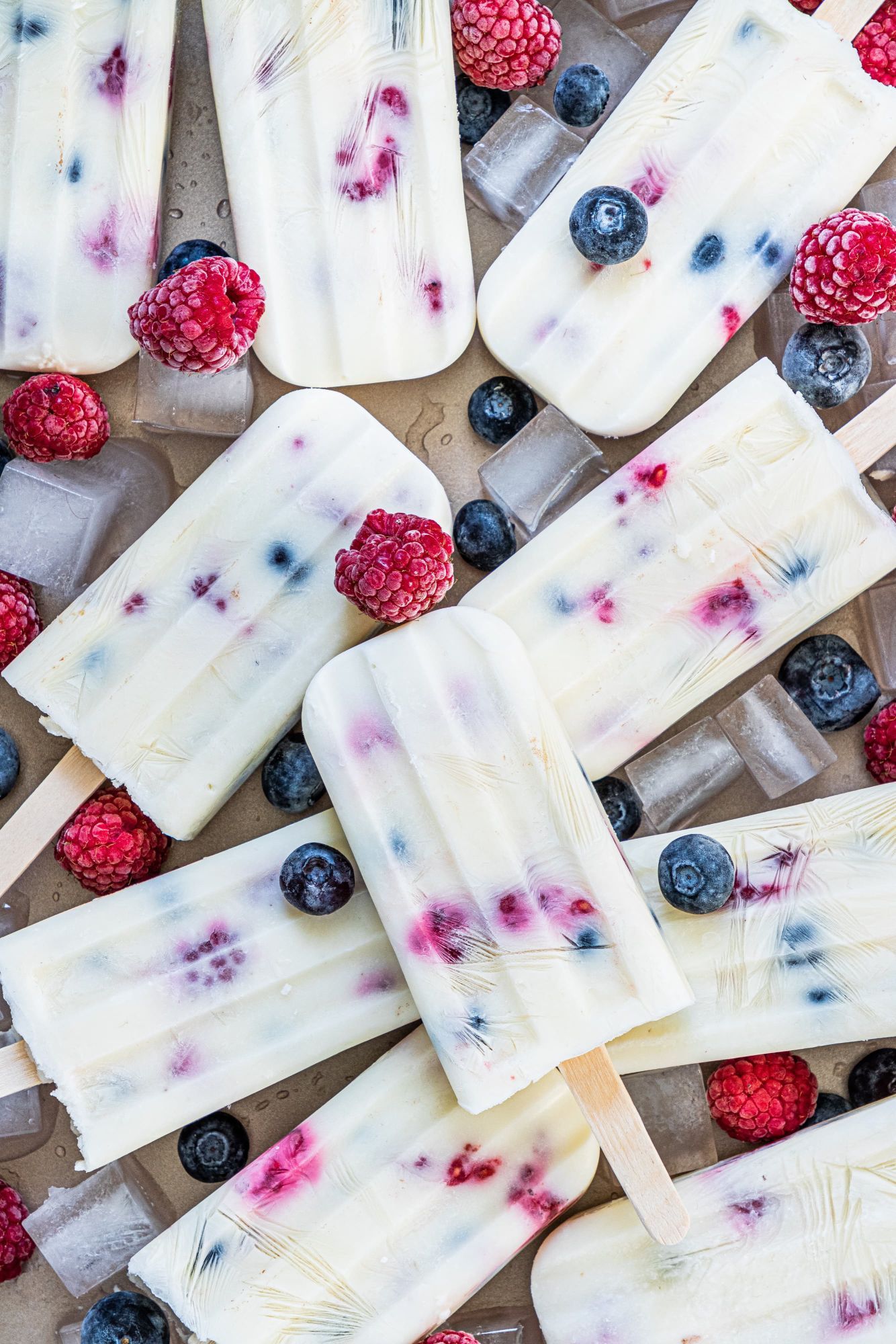 Yogurt and fruit popsicles with creamy yogurt, raspberries, blueberries, and strawberries with wooden sticks.