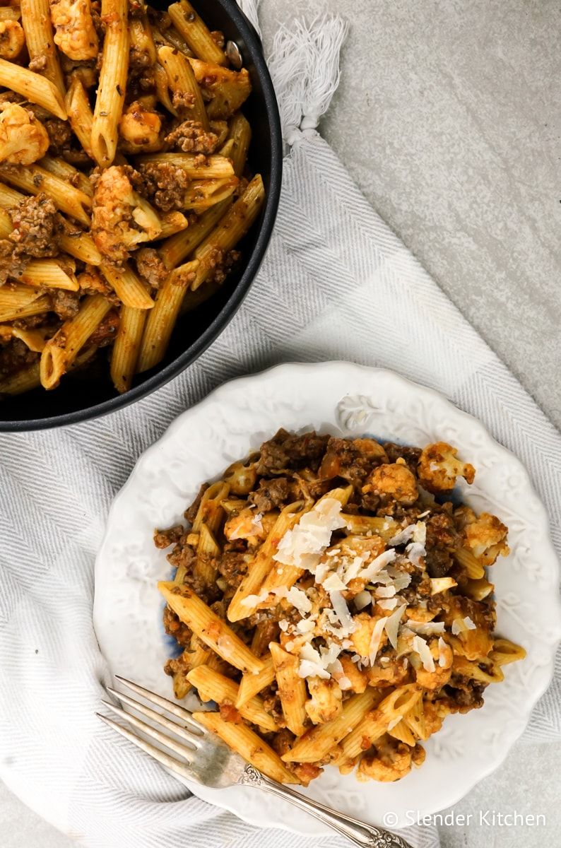 Garlic Cauliflower and Sausage Pasta served in a skillet and on a plate.