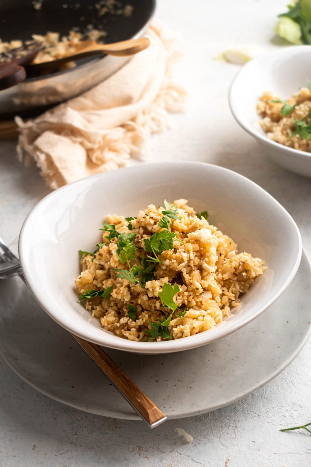 Cauliflower rice with garlic and Parmesan cheese in a bowl topped with parsley.