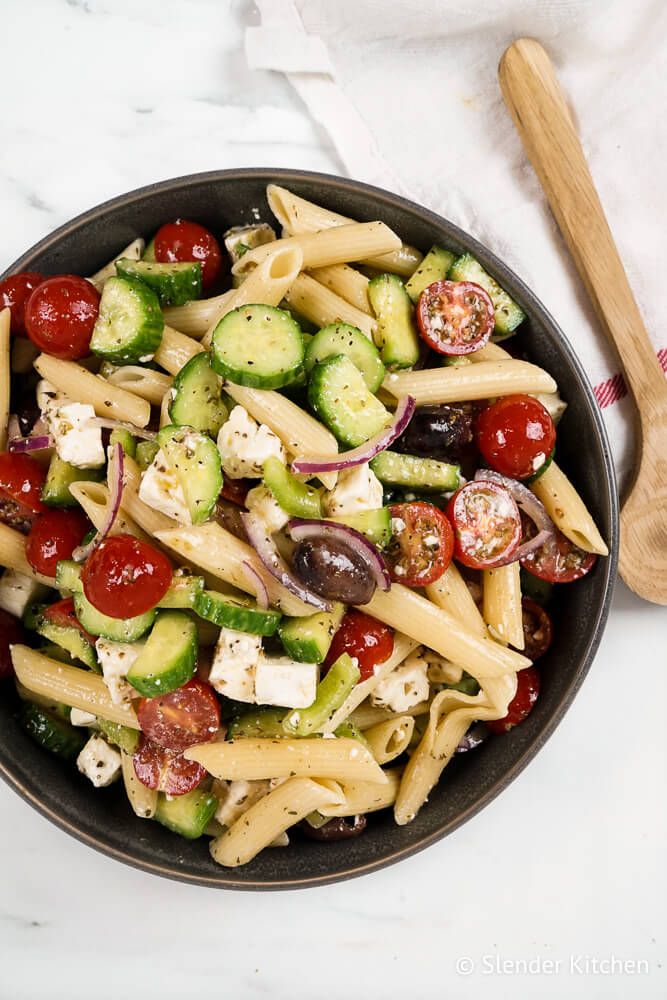 Pasta salad with Greek flavors including feta cheese, cucumbers, tomatoes, red onions, and feta cheese.