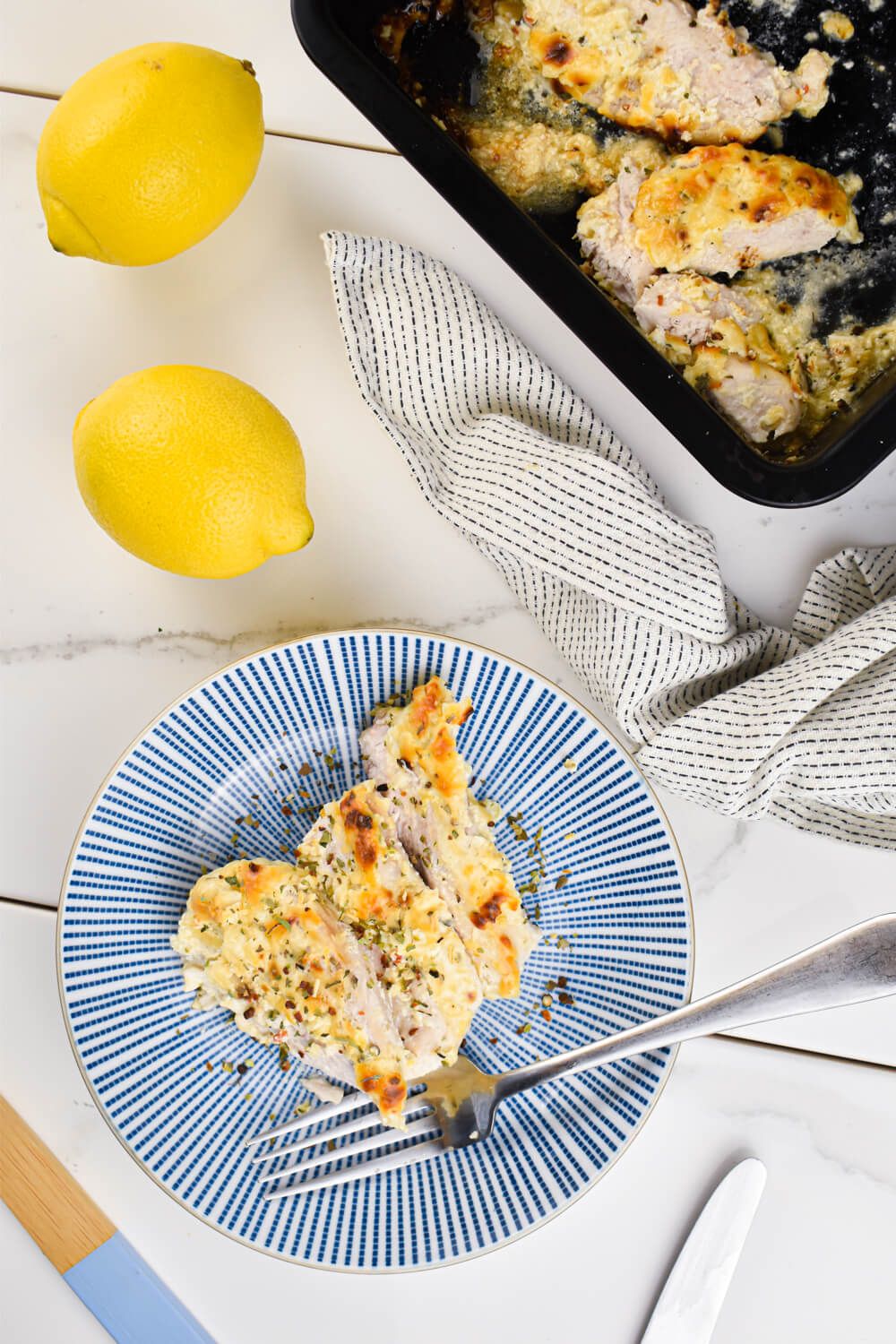 Greek Yogurt Chicken with Parmesan cheese, lemon juice, garlic, and spices sliced on a blue plate.